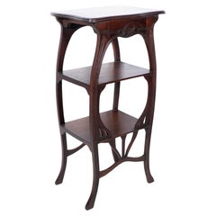 An Art Nouveau mahogany three tier plant stand with shallow floral carving