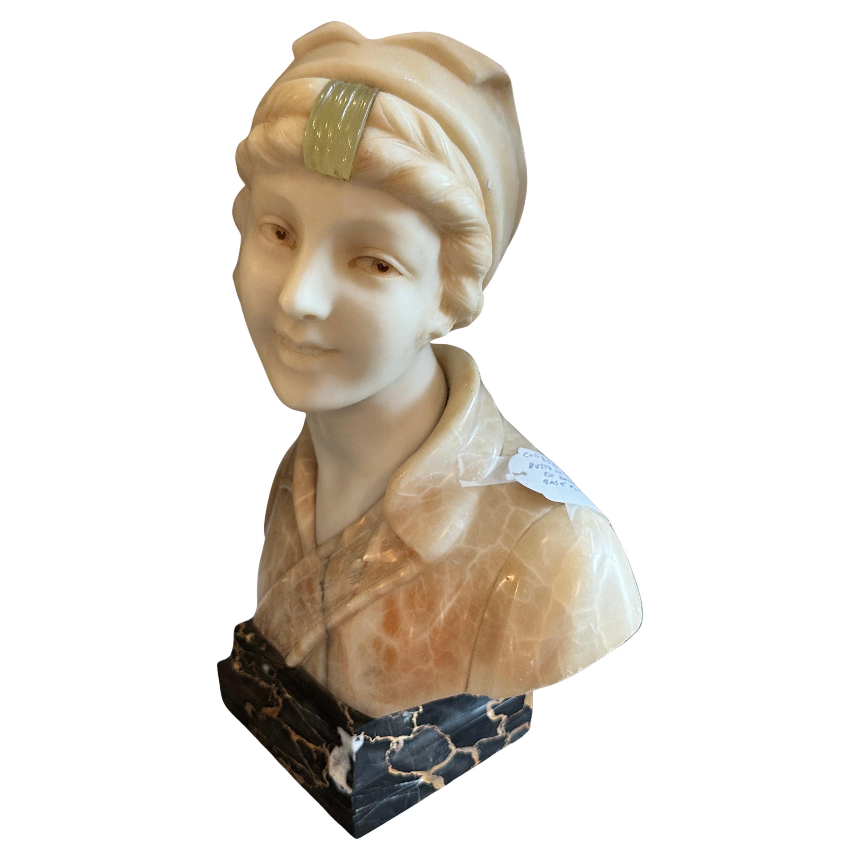 Questo affascinante busto in marmo Art Nouveau ritrae una giovane ragazza dall'espressione serena e gentile. La scultura è realizzata in marmo con sottili venature che conferiscono al pezzo un tono morbido e caldo. La sua testa è ornata da un