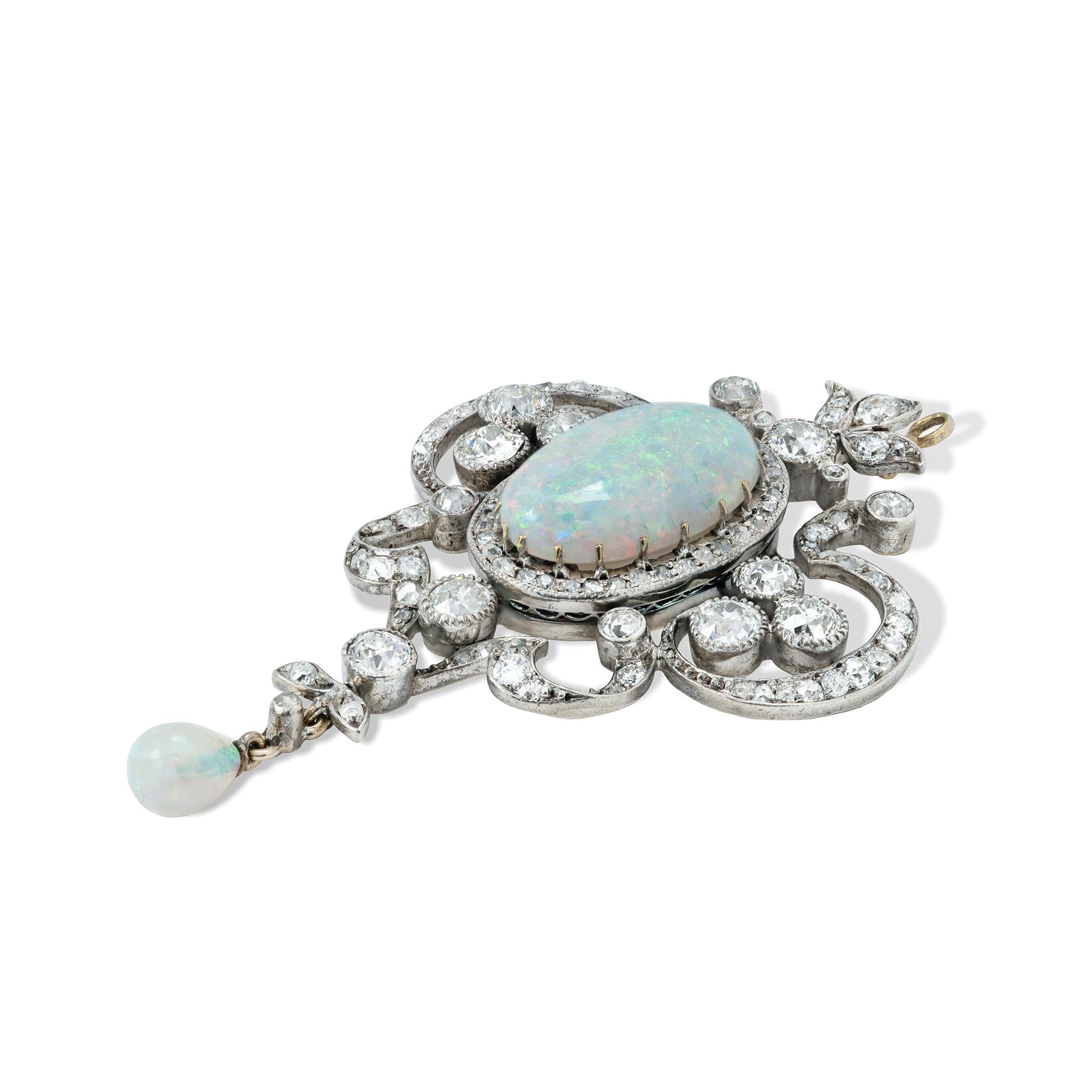 An Art Nouveau opal and diamond pendant, the central oval-shaped cabochon-cut opal weighing approximately 5 carats, set within a cluster of old-cut diamonds in an openwork scrolling diamond-set foliate surround, suspending a smaller opal drop, all