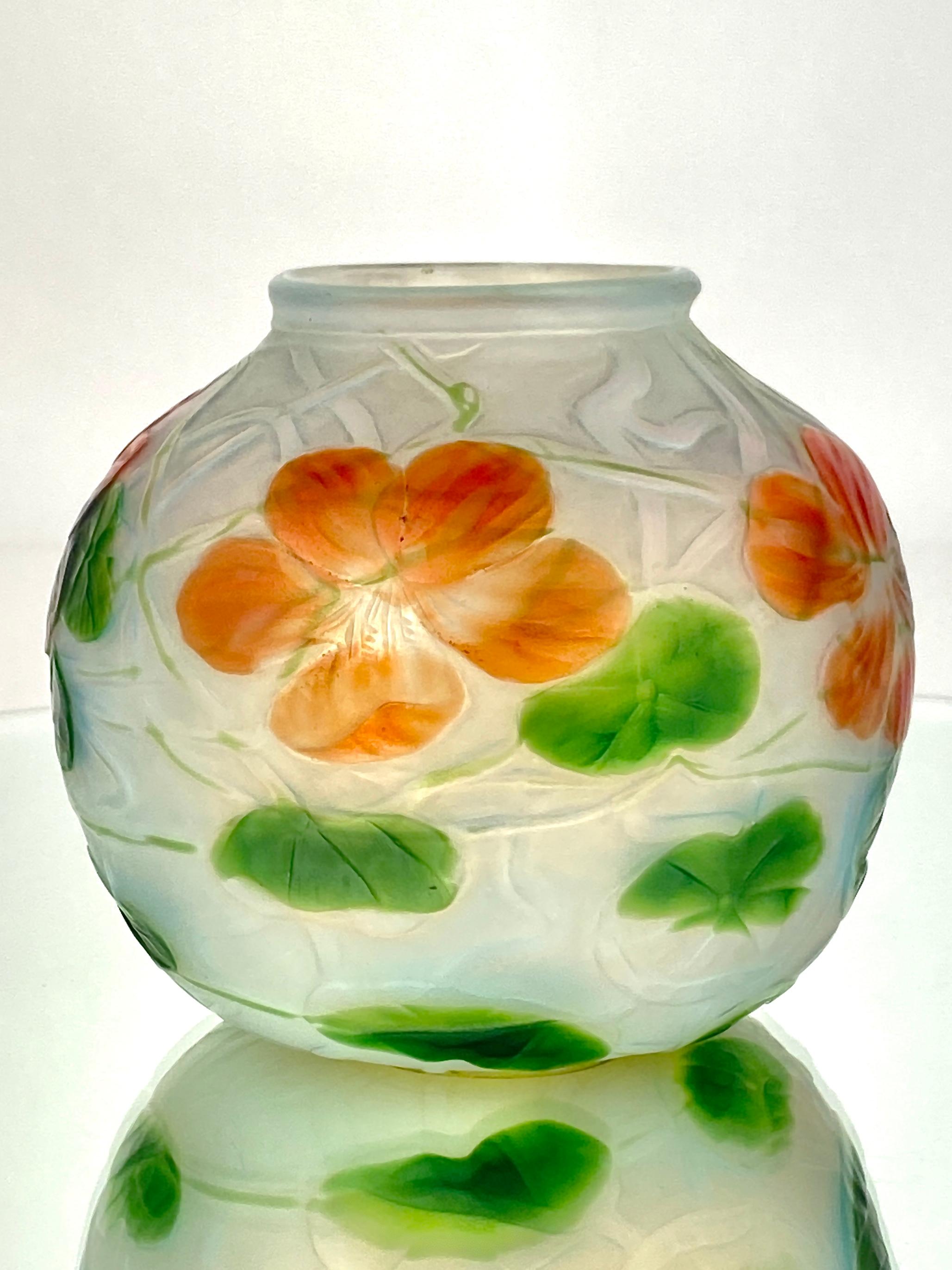 An American Art Nouveau blown glass Tiffany Favrile wheel-carved Nasturtium vase by, Tiffany Studios. The vase is round shaped and features a band of orange-red nasturtiums and green lily pads and vine decoration against an opalescent carved glass