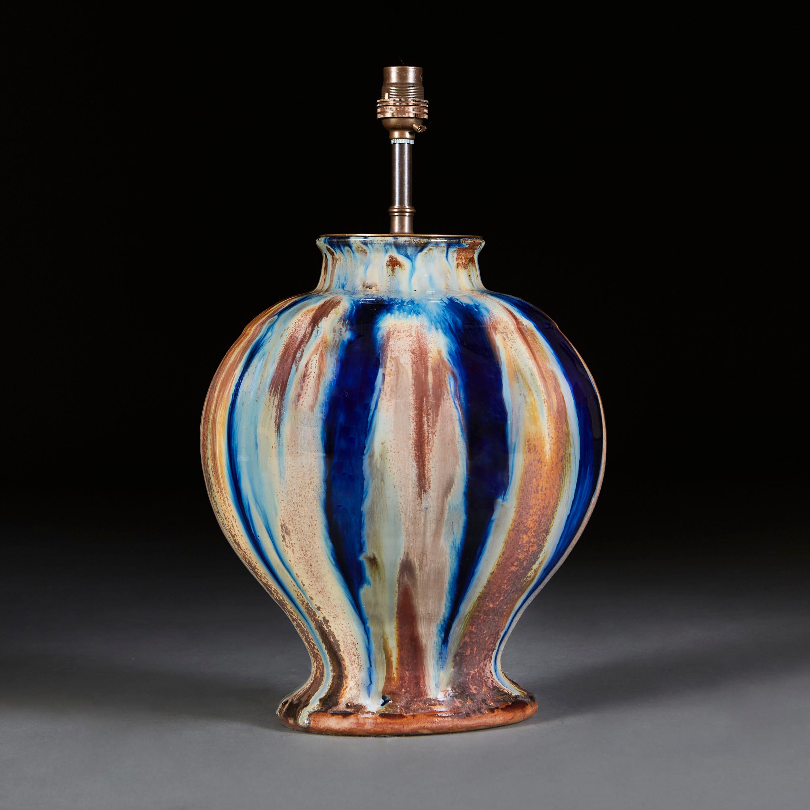 A mid twentieth century art pottery vase, with blue and cream drip glaze throughout, now wired as a lamp.

Currently wired for the UK with twisted bronze silk flex. Please enquire for rewiring services. 

Please note: lampshade not included.