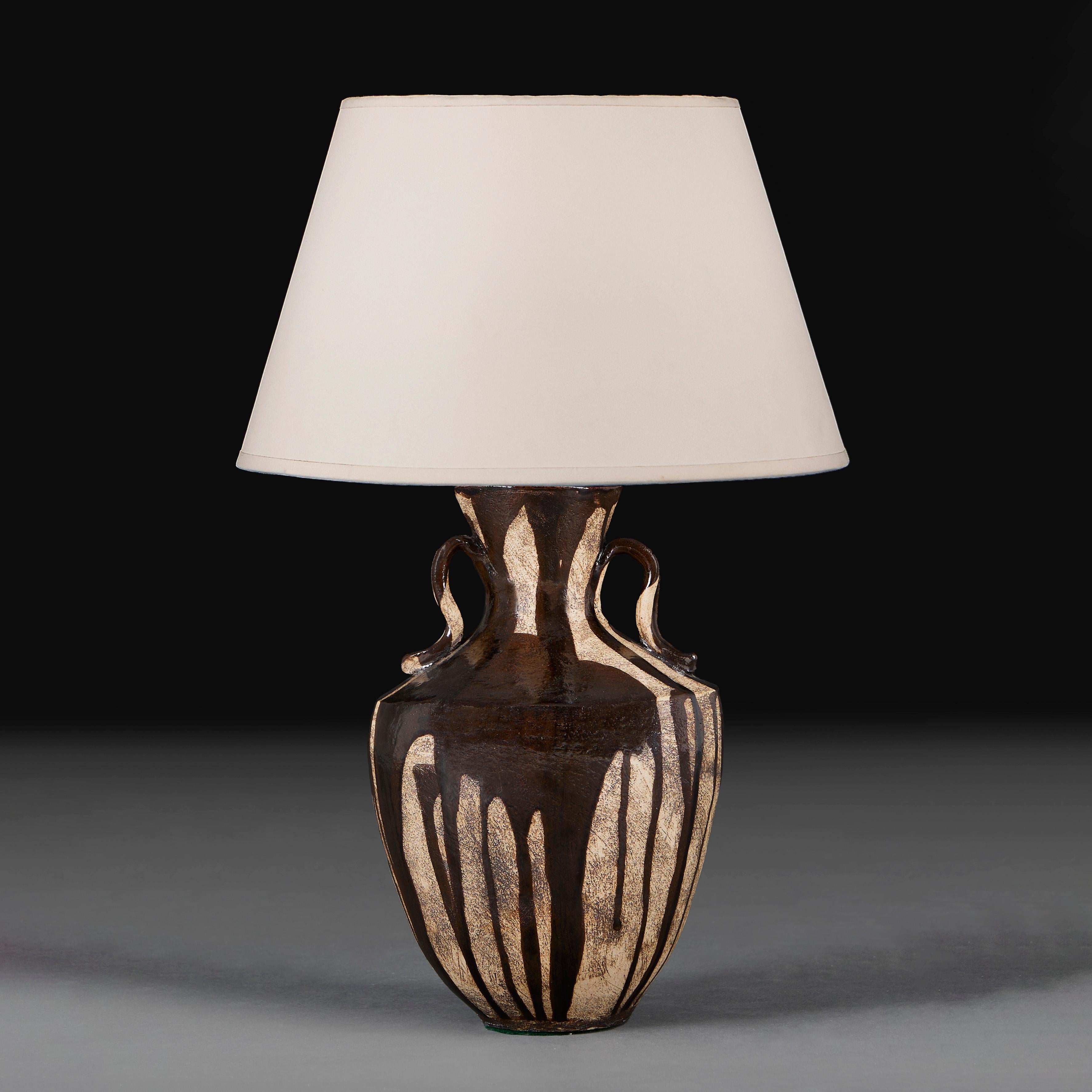 A mid twentieth century art pottery vase of amphora form, with unglazed sand background, overlaid with chestnut brown drip glaze, now as a lamp. 
England, circa 1940
Height of vase            32.00cm
Height with shade     55.00cm
Diameter of base   