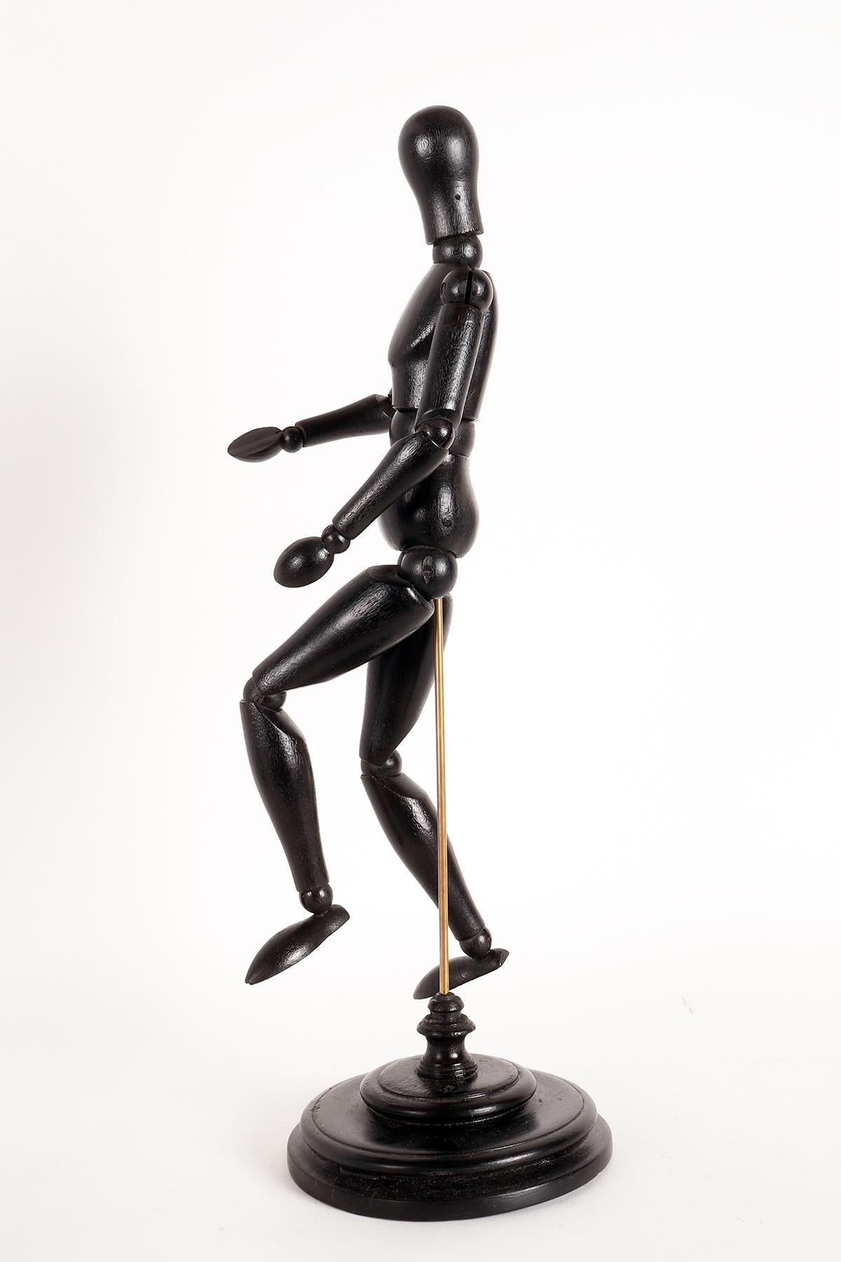 An articulated mannequin of a small-sized painter, with a metaphysical face. The mannequin is made of carved and ebonized fruit wood. The support is in brass and the base, also made in a round shape in ebonized fruitwood. France, circa 1920.