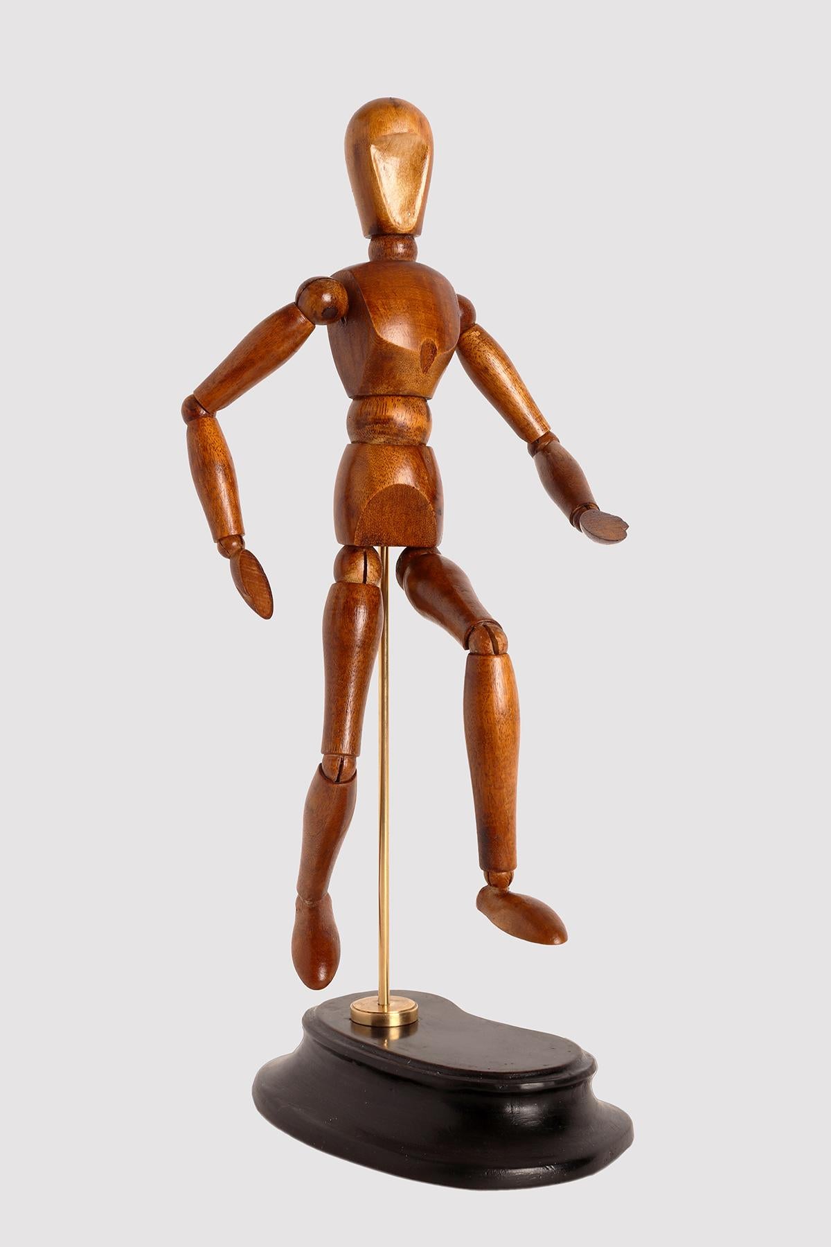 An articulated mannequin of a small-sized painter, with a metaphysical face. 
The mannequin is made of carved mahogany wood. The support is in brass and the base, 
made out of ebonized fruit wood. France, circa 1940.