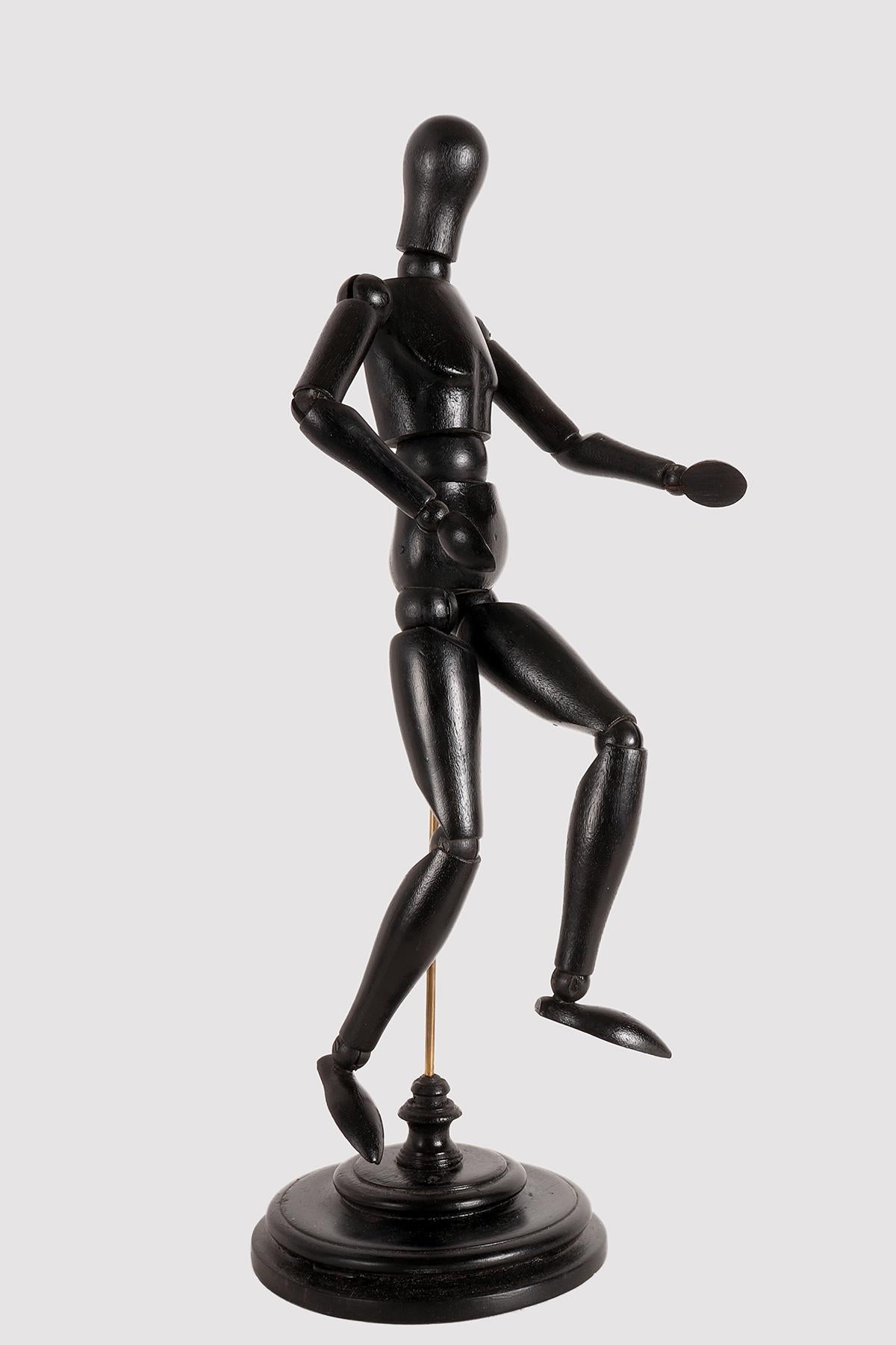 An articulated mannequin of a small-sized painter, with a metaphysical face. The mannequin is made of carved and ebonized fruit wood. The support is in brass and the base, also made in a round shape in ebonized fruitwood. France, circa 1920.