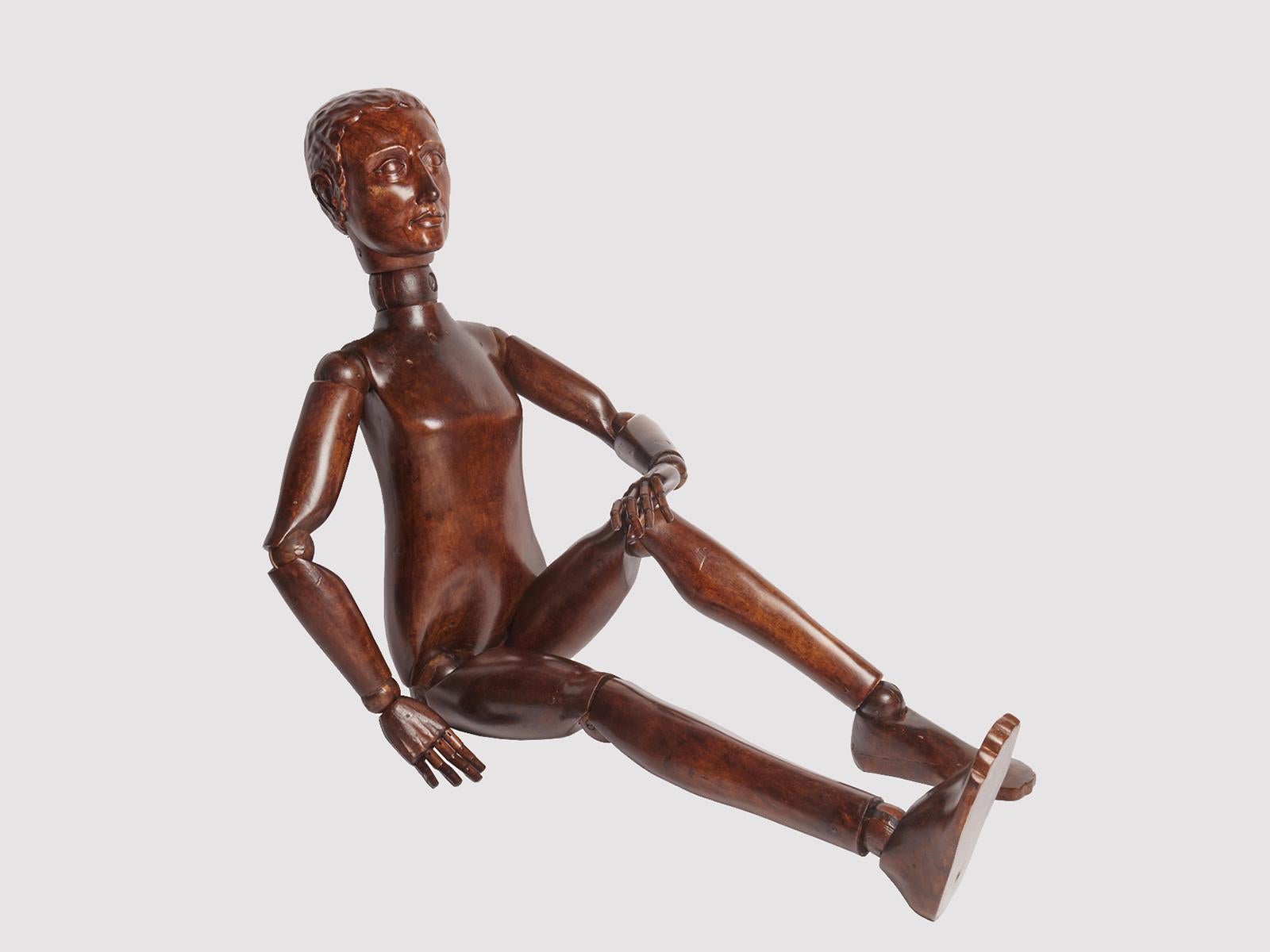 Maniquí articulado de pintor, que representa a un adolescente, de tamaño natural. El maniquí es de madera de nogal, las esferas articuladas son de madera de arce. Las extremidades están totalmente articuladas, al igual que la cabeza. El rostro es el