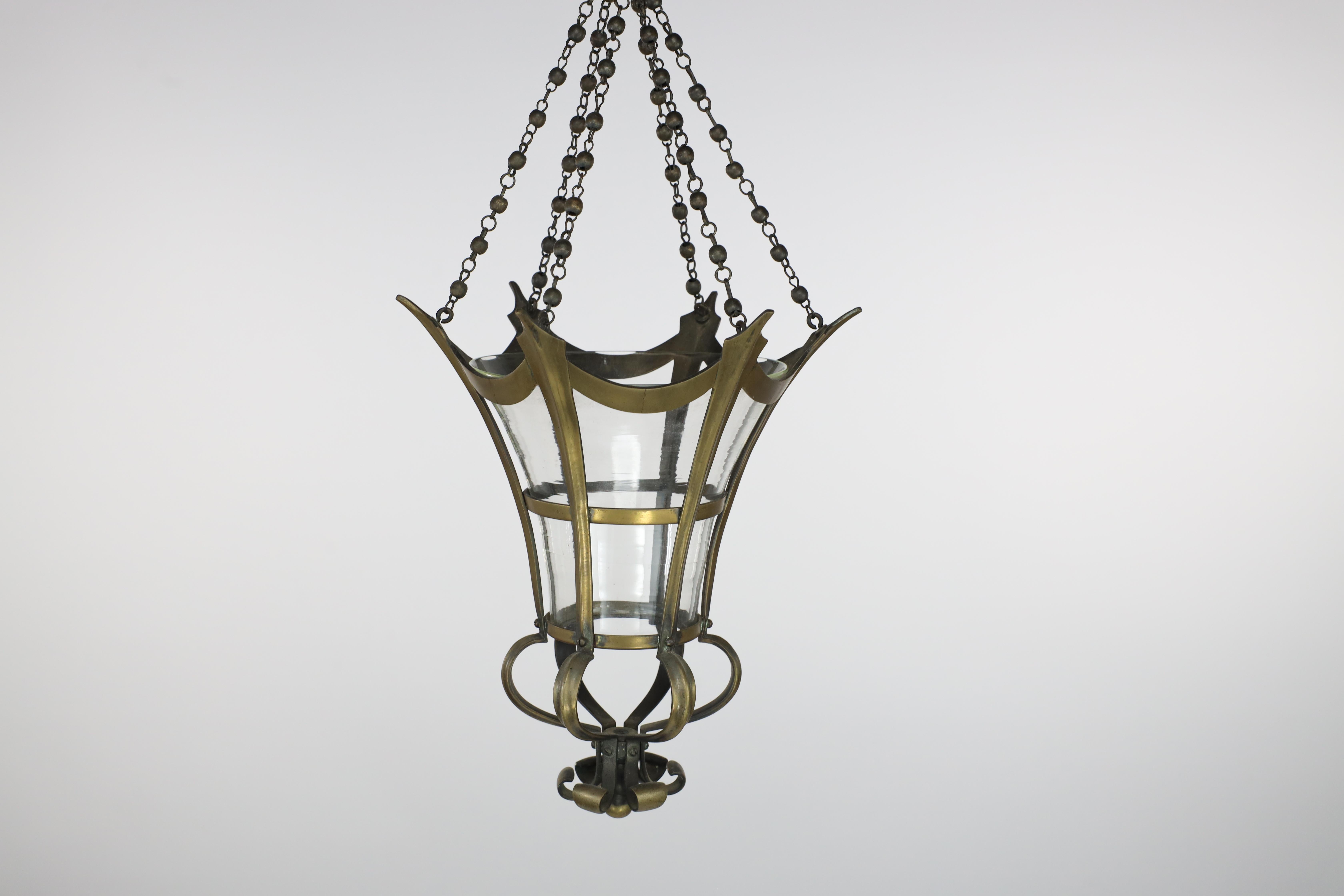 An Arts and Crafts brass hexagonal and conical-shaped lantern, with the original conical shade, each brass fluted side flows down and opens into a sphere and then unites into a flower at the base of the light. Retaining the original tiny ball and