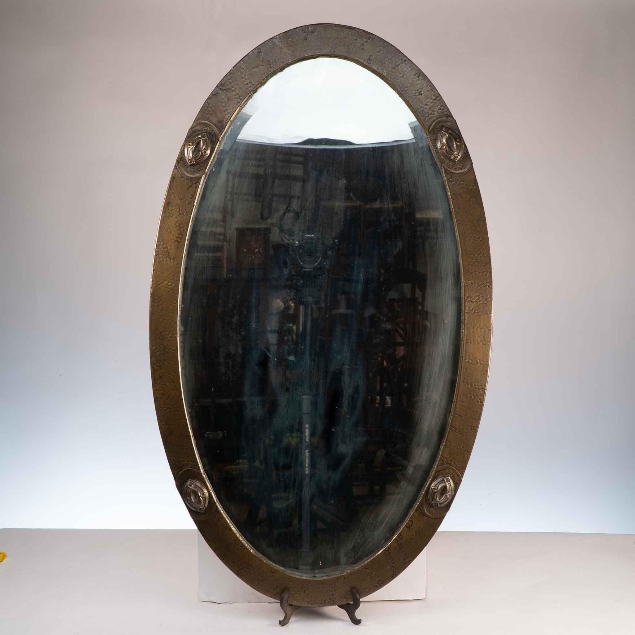 Miroir en laiton martelé à la main, de style Arts and Crafts, avec quatre détails de style celtique et un miroir biseauté.