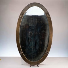 An Arts and Crafts brass hand hammered mirror with four Celtic style details