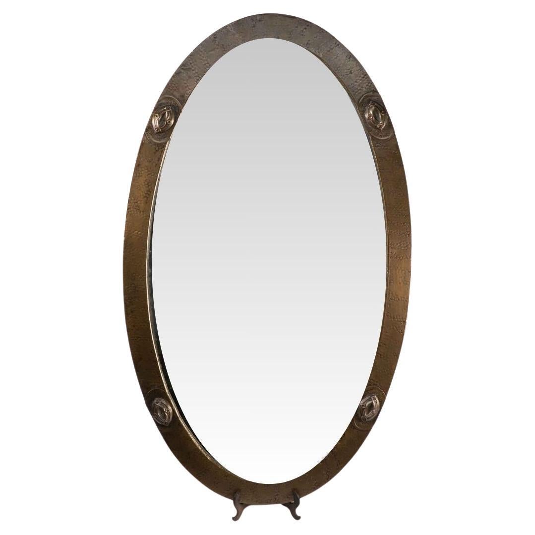 An Arts and Crafts brass hand hammered mirror with four Celtic style details