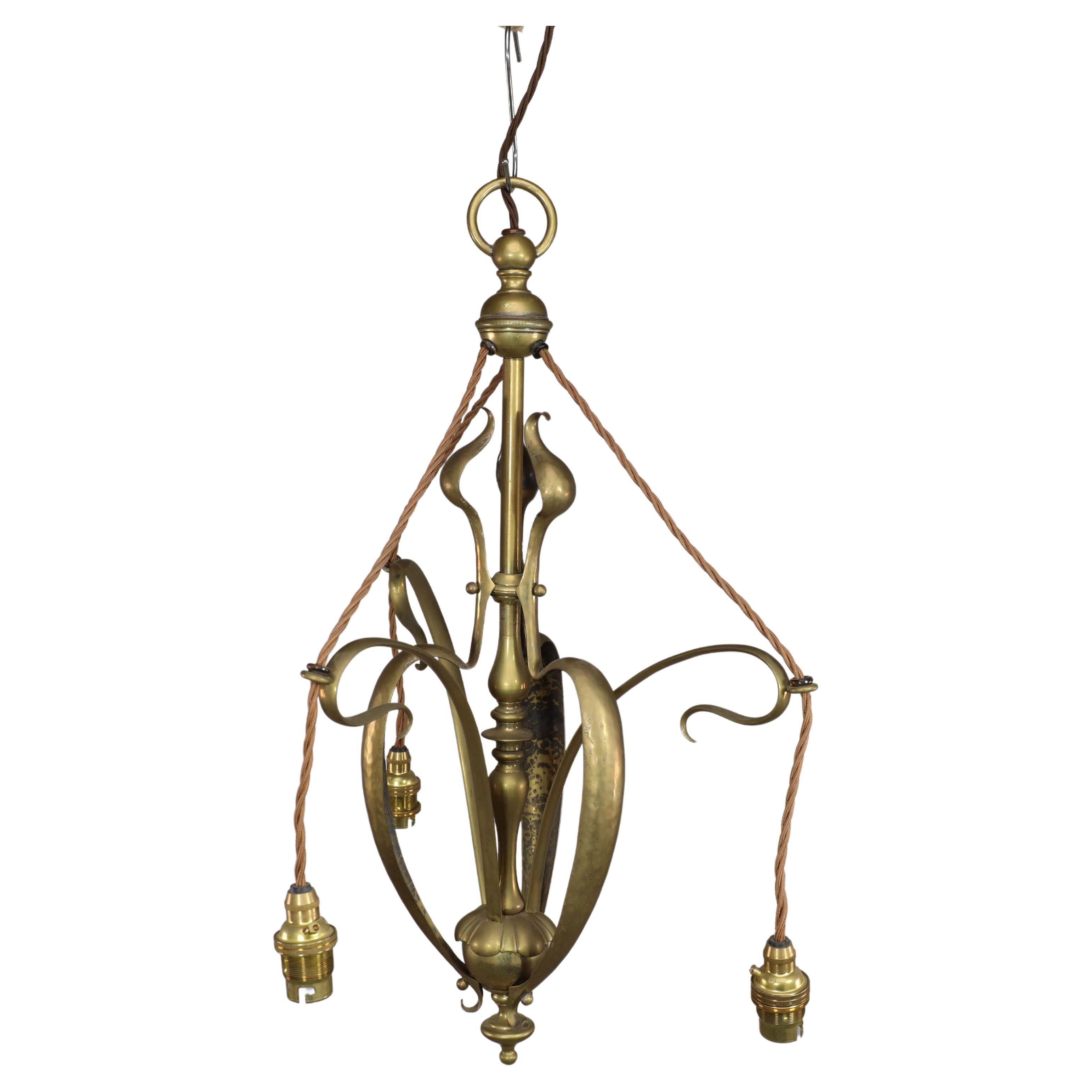 An Arts and Crafts brass three arm ceiling light