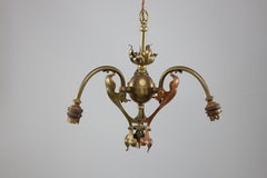 An Arts and Crafts brass three arm ceiling light with a flower bud to the top