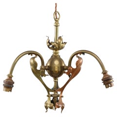 An Arts and Crafts brass three arm ceiling light with a flower bud to the top