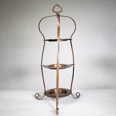An Arts and Crafts copper cake stand with three matching copper plates