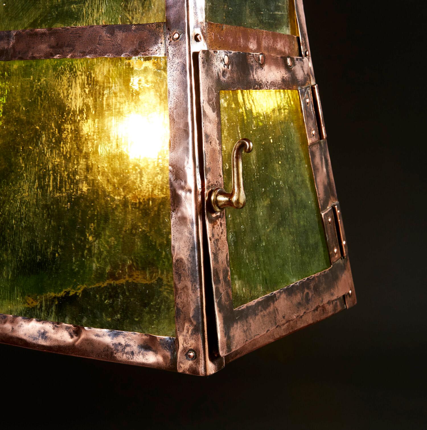 As unusual Arts & Crafts copper hanging lantern in the form of a pagoda, with textured green glass sides, the front opening with a door and a brass handle. 

Please note that this lantern is currently wired for the UK.
 