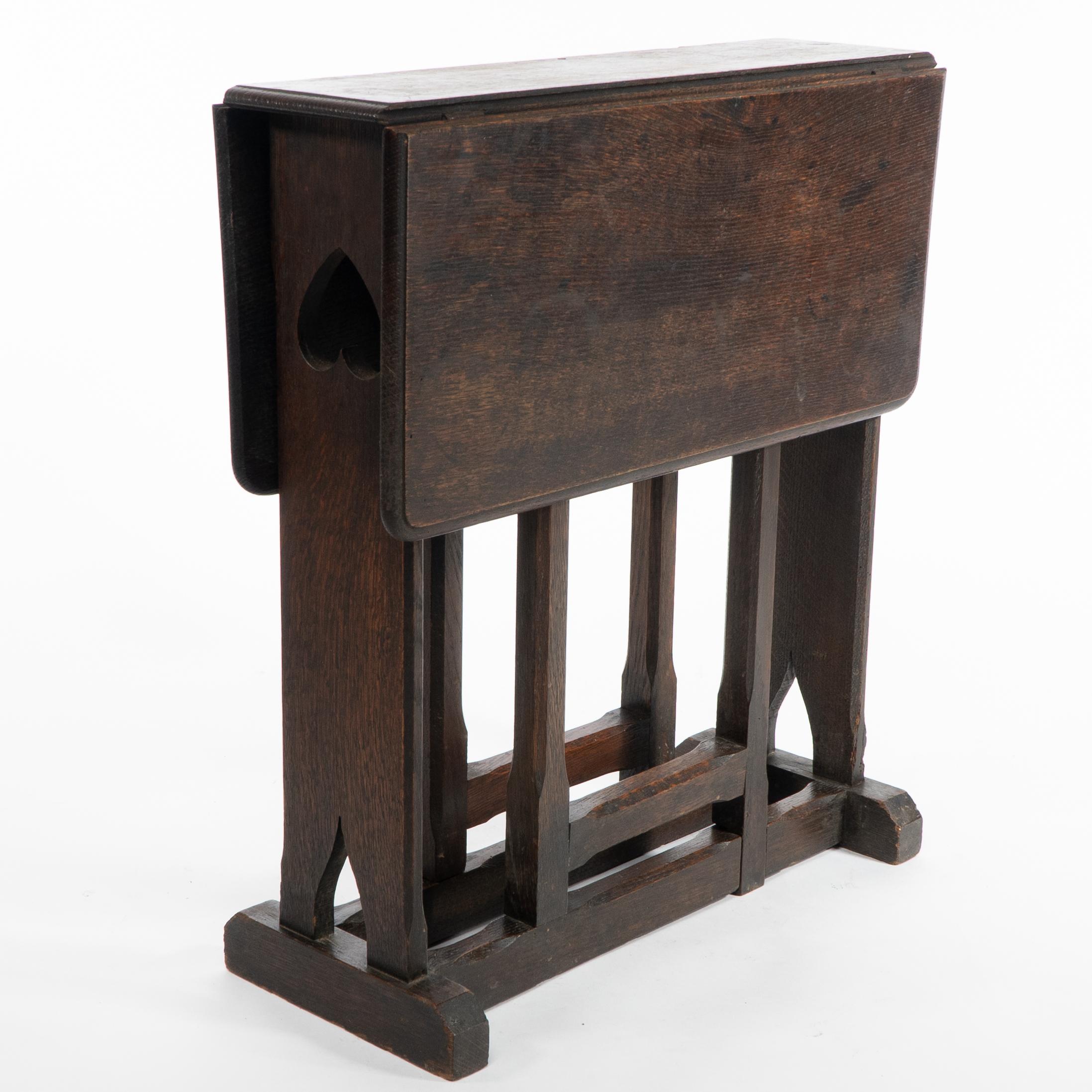 Table à thé ou d'appoint en chêne de style Arts and Crafts, avec des pieds en forme de porte, une décoration en forme de cœur percé à chaque extrémité et des détails chanfreinés sur l'ensemble de la table, posée sur une base de style