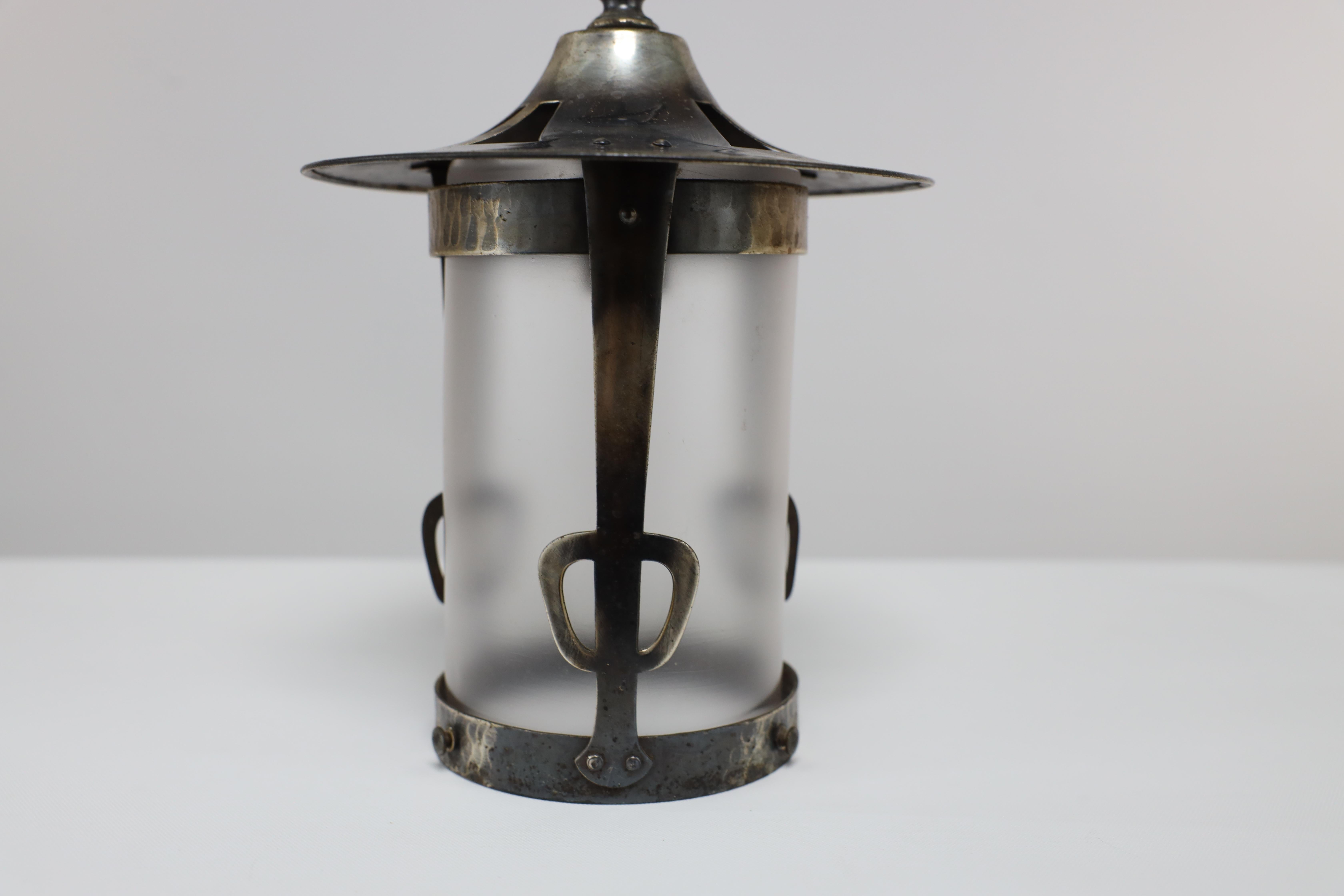 An Arts and Crafts Glasgow School hand-hammered copper lantern with a flaring top and the original opaque shade.