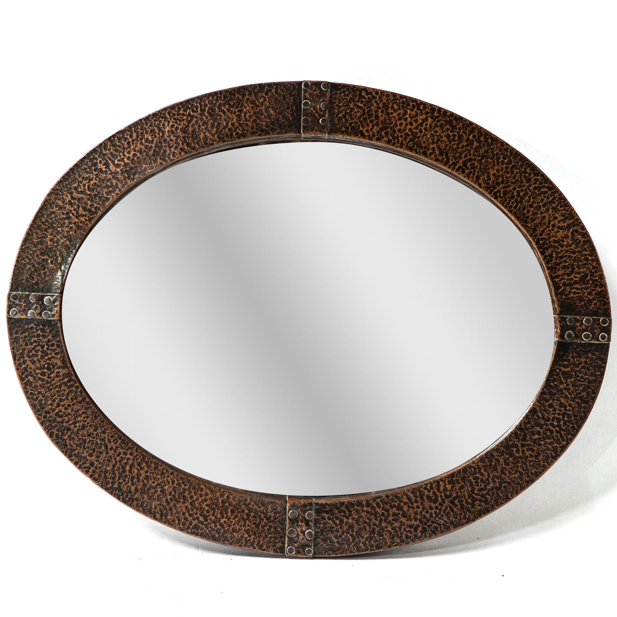 Miroir ovale en cuivre martelé à la main, de style Arts and Crafts, avec sangles rivetées et miroir biseauté d'origine.