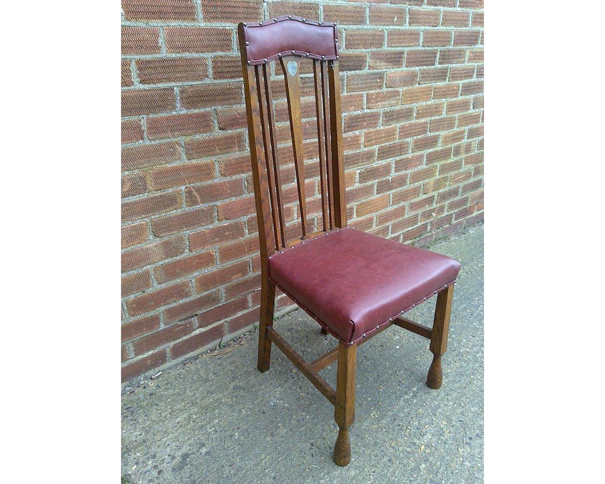 Liberty & Co, attributed. Probably made by Shapland and Petter.
An Arts and Crafts oak chair with shaped padded head rest with a single Voysey style inlaid pewter heart to the top of a fine tapering back splat with trumpet style feet,