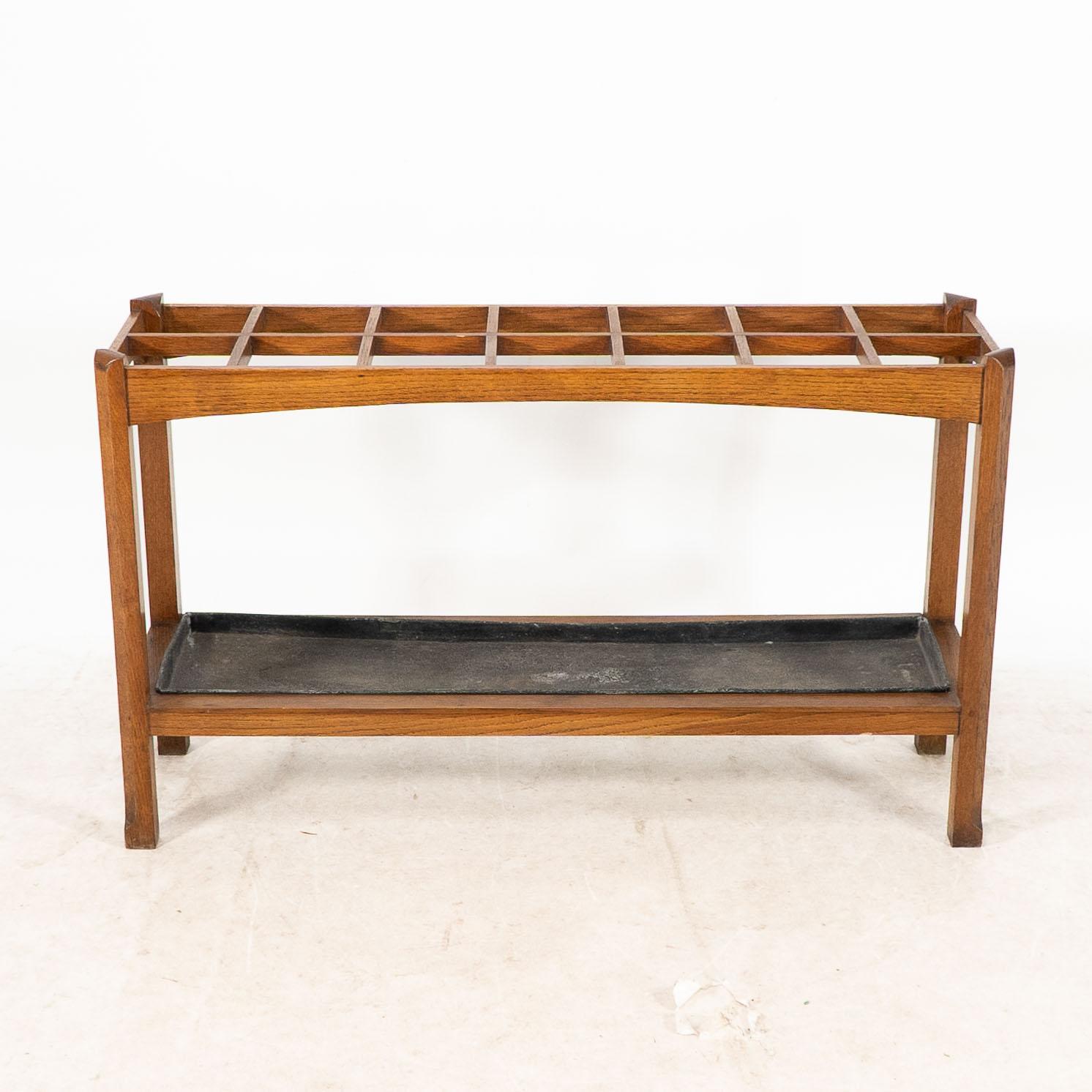 An Arts and Crafts oak stick and umbrella stand with fourteen sections for different placements of your walking sticks.