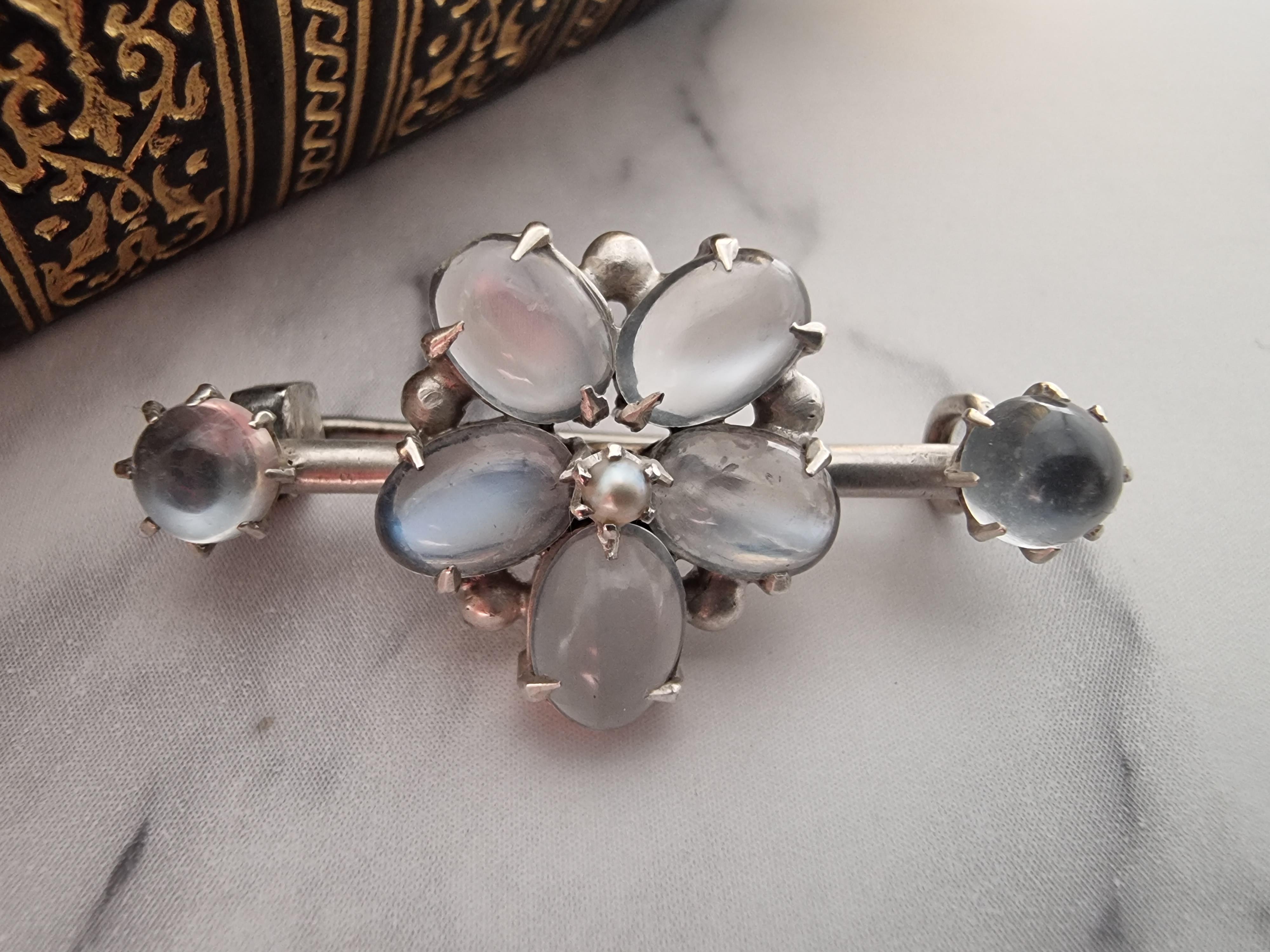 A most beautiful and fine silver arts and crafts brooch, unmarked (tested).

This fine bar brooch is set with seven good sized moonstones, it has one single stone at each end with a large flower head in the centre made up of five large petal shaped