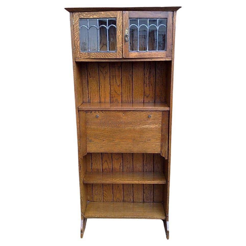 Una librería buró alta Arts and Crafts de roble con puertas de cristal emplomado