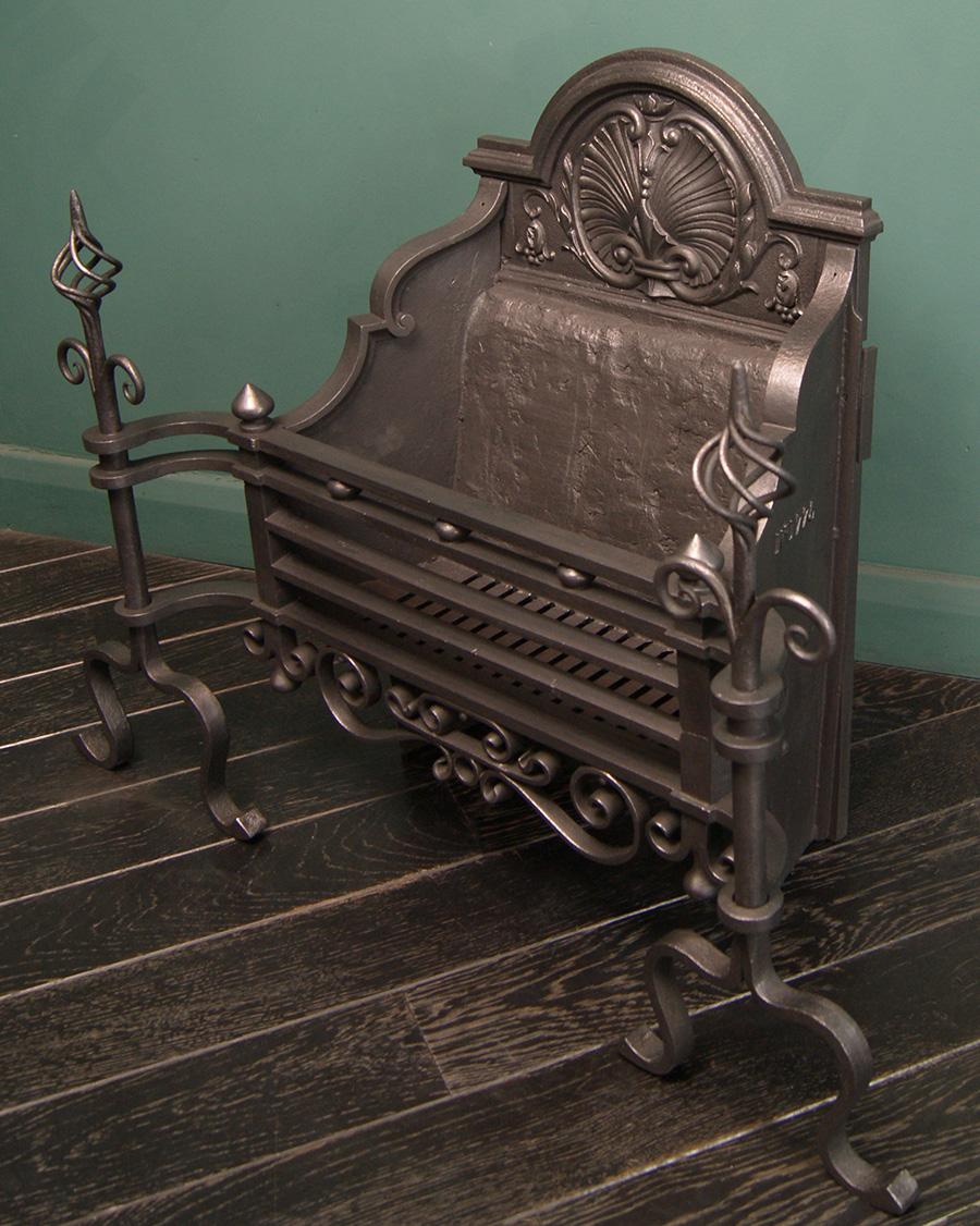 An Arts & Crafts black wrought fire grate with black spheres set between upper fire bars, a scrolled fret and nest finials uppermost. The decorative fire back with central shell and cartouche.  Restored.

Circa 1860