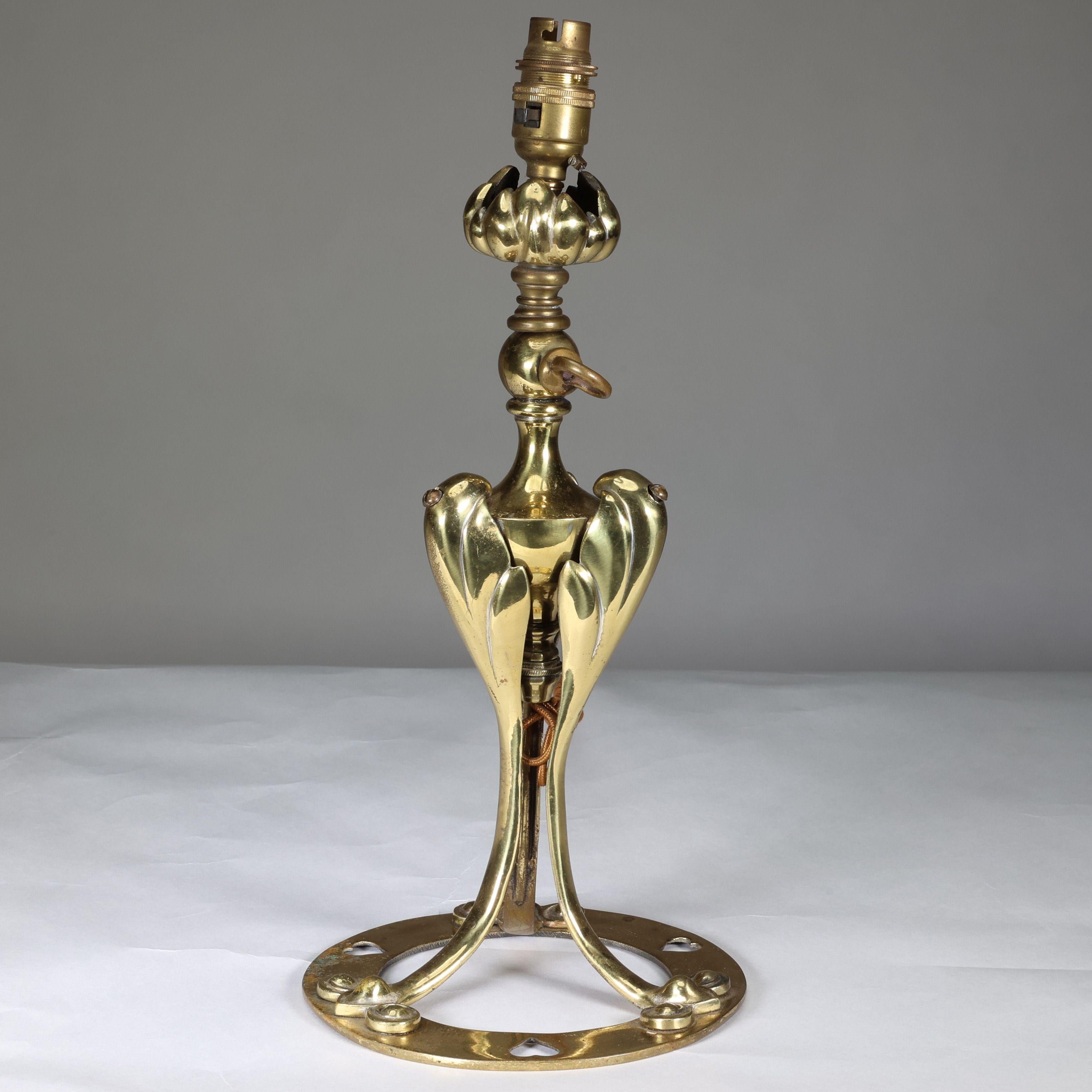 An Arts and Crafts brass table lamp in the style of a flower with circular base pierced with hearts.