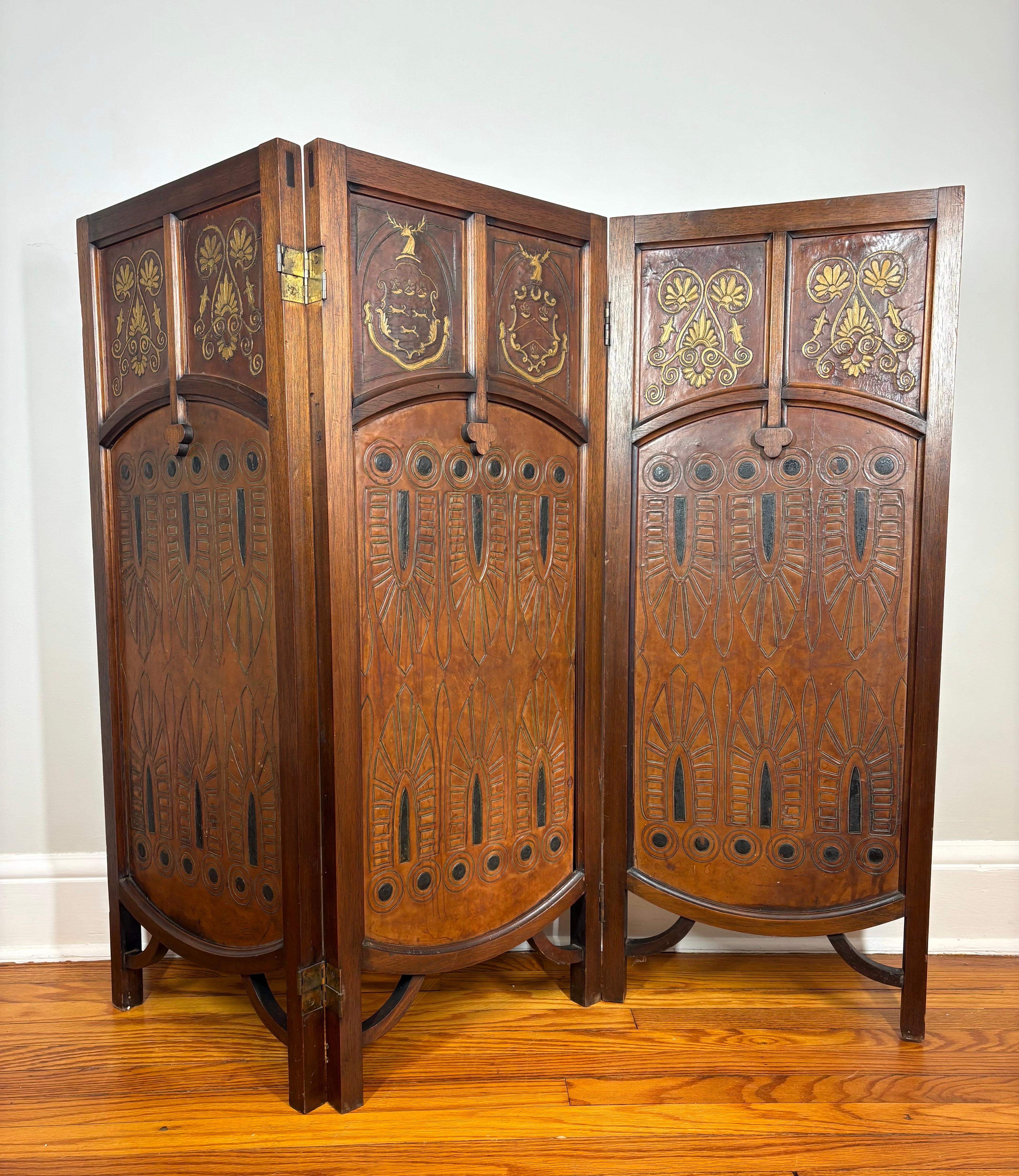 Paravent/séparateur à trois panneaux en cuir gaufré et en noyer, doré, d'époque Arts and Crafts anglaise, vers 1890. Le panneau central présente des armoiries dorées, le reste des motifs décoratifs étant typique de l'esthétique Arts and Crafts.

Né