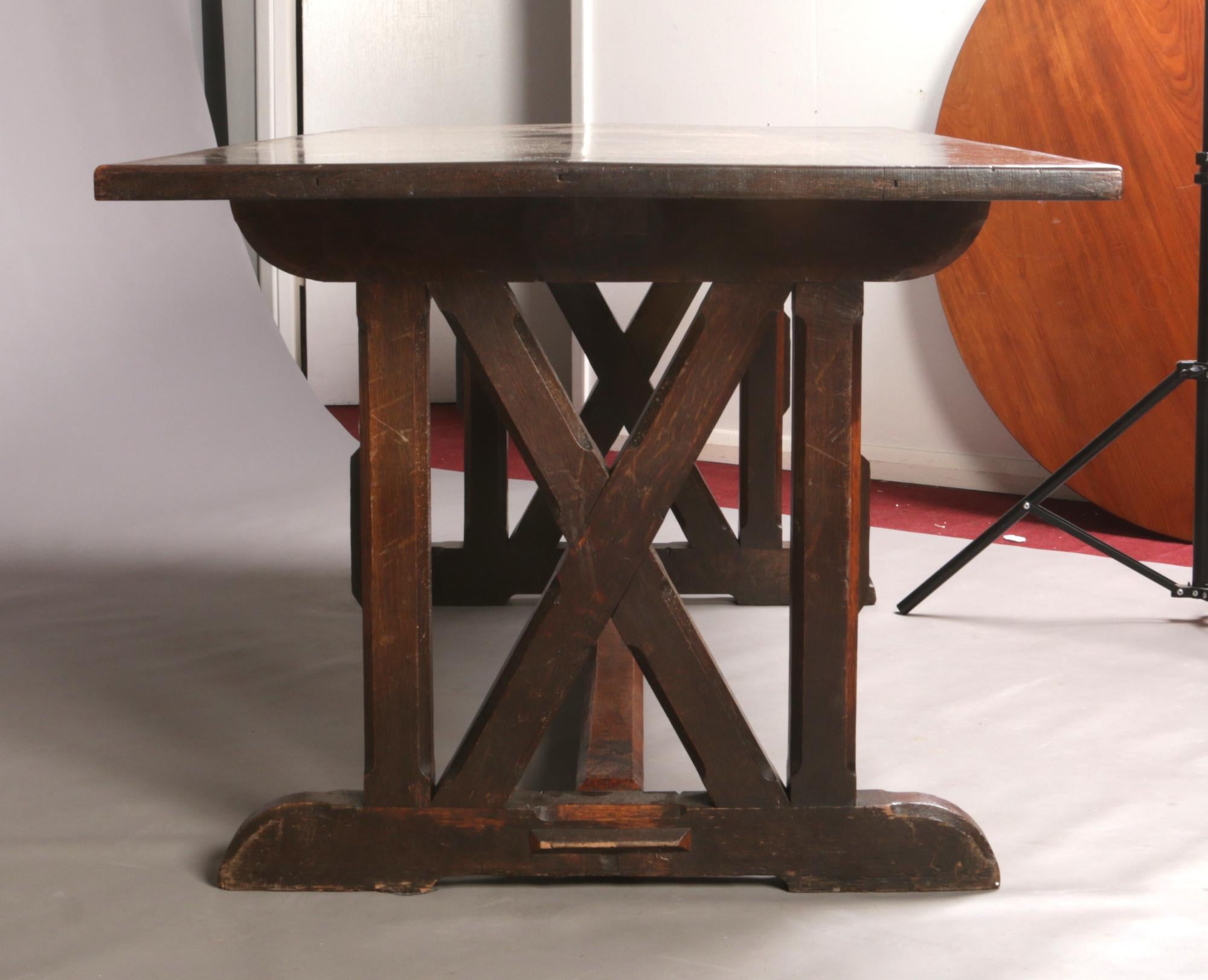 Liberty & Co, attributed. An Arts & Crafts Cotswold School oak refectory dining table.
With cross framed details to each end, united by a floor stretcher with exposed decorative style through tenon joints and chamfered details.
The table top with