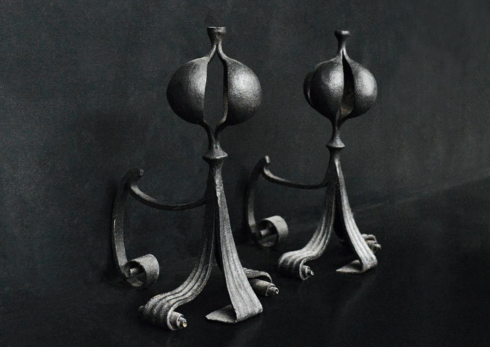 A pair of Arts & Crafts firedogs. The scrolled feet surmounted by gadrooned finials. English, early 20th century. (Blacked but could be polished if required.)

Height:	490 mm      	19 ¼
