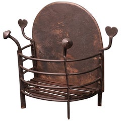An Arts & Crafts Semi-Circular Wrought Fire Basket with Heart-Shaped finials