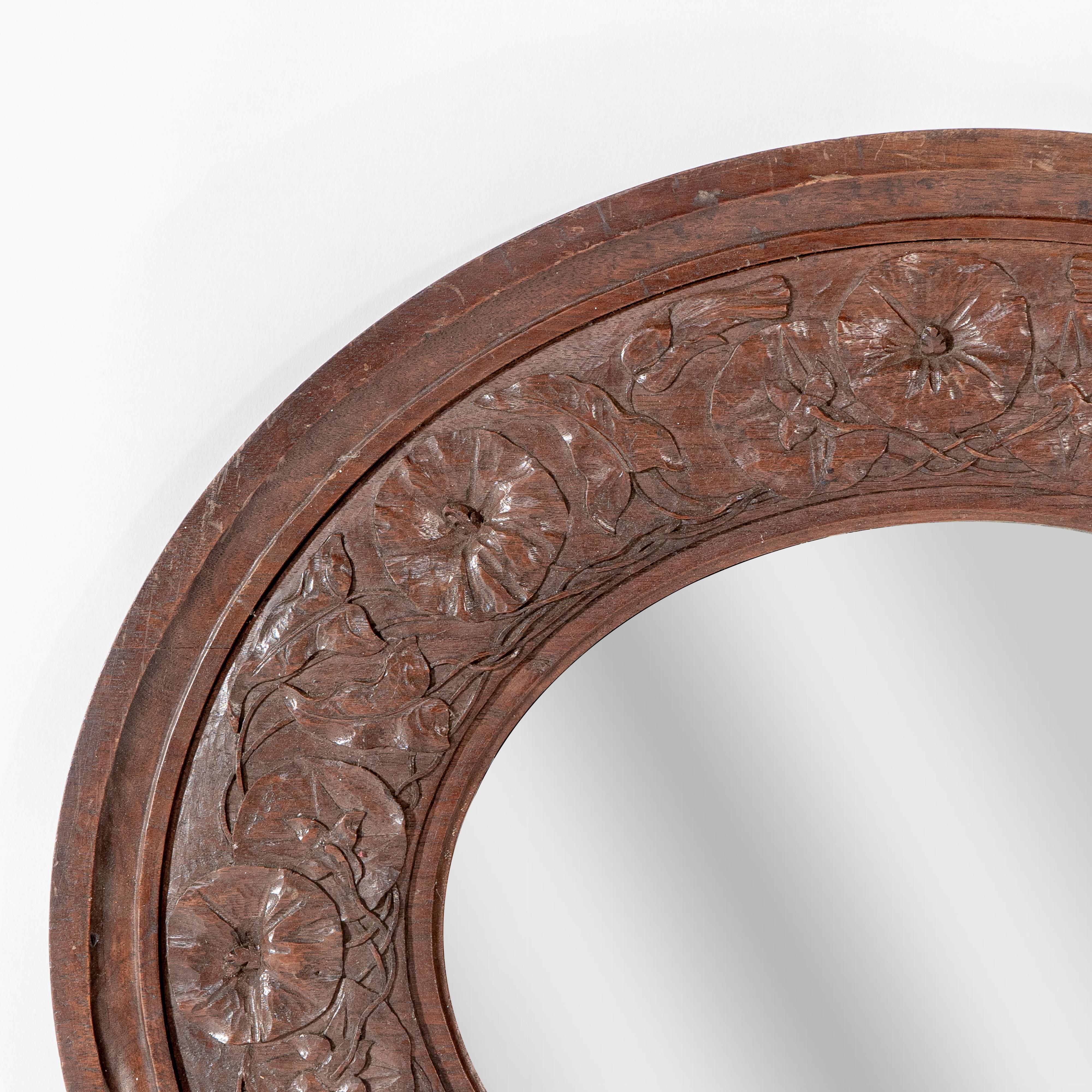 Arts and Crafts An Arts & Crafts walnut circular mirror with stylized floral carved decoration For Sale