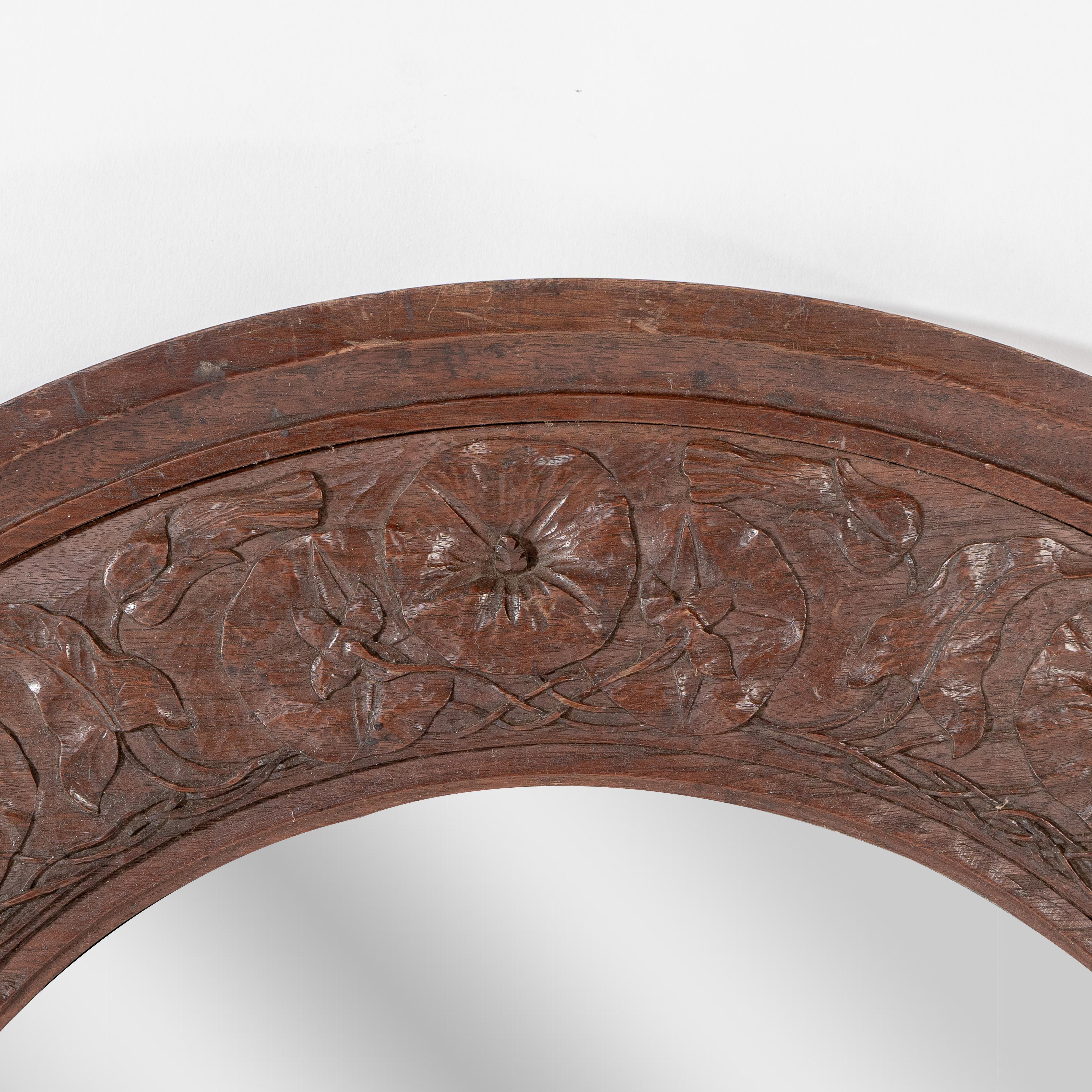 English An Arts & Crafts walnut circular mirror with stylized floral carved decoration For Sale