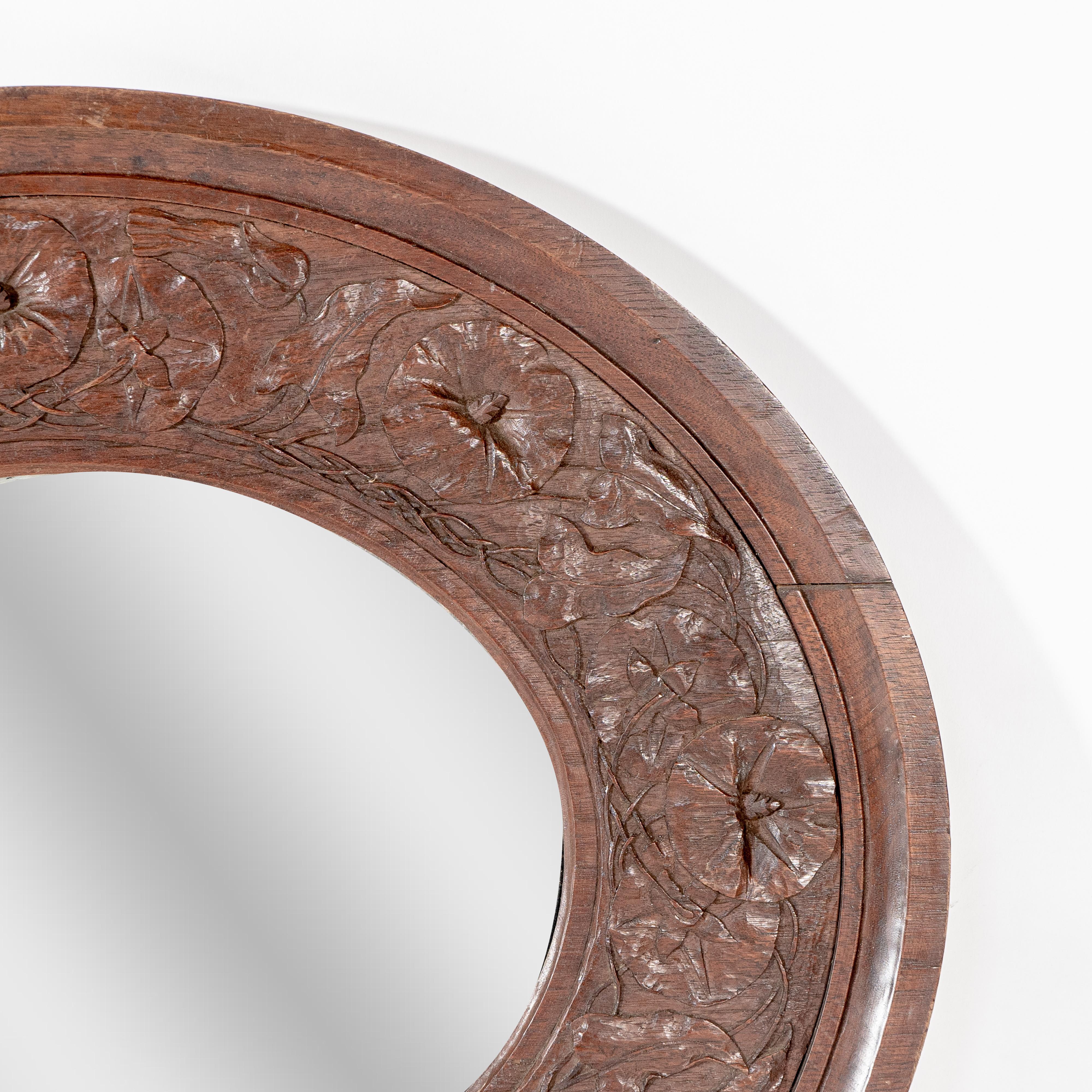 An Arts & Crafts walnut circular mirror with stylized floral carved decoration In Good Condition For Sale In London, GB
