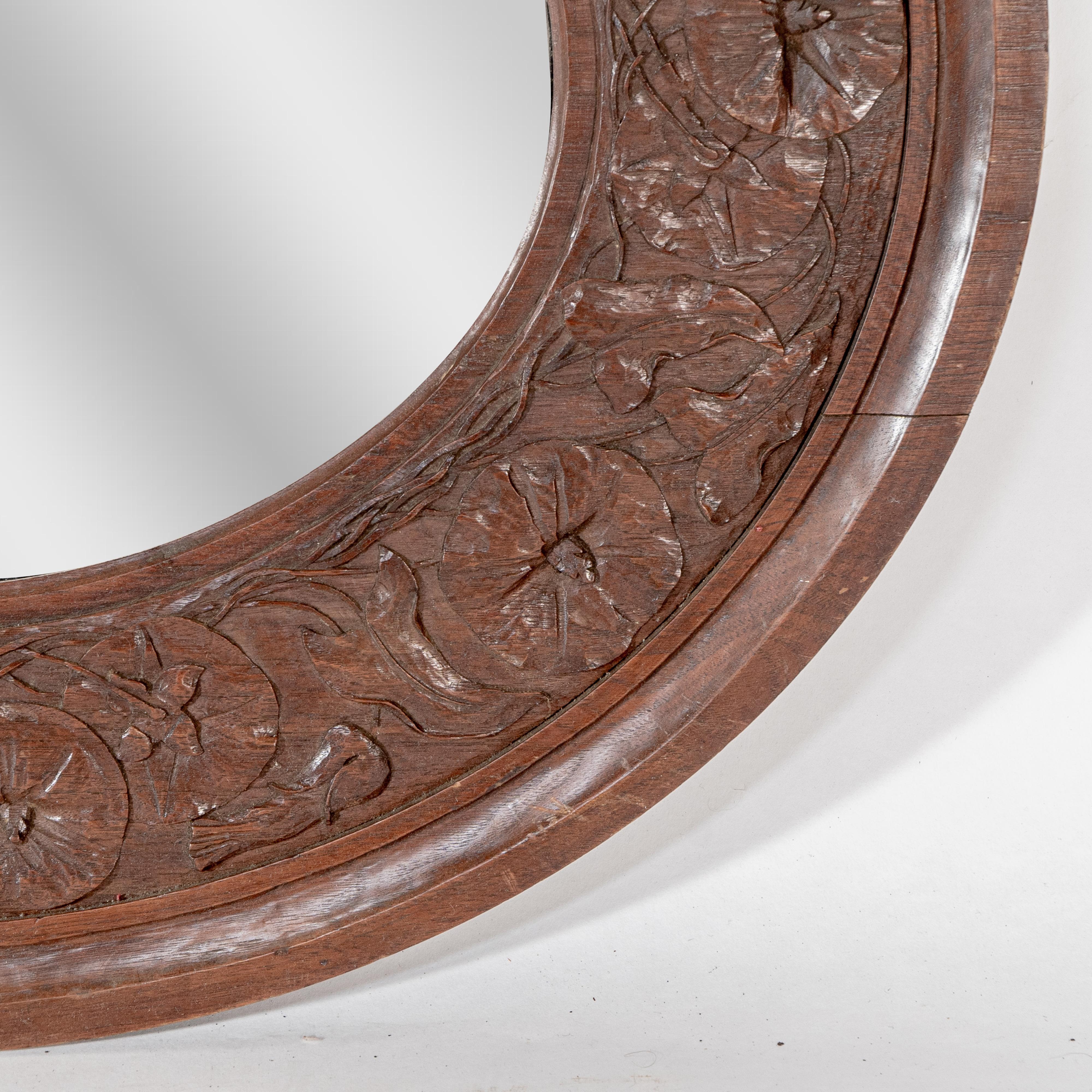 Early 20th Century An Arts & Crafts walnut circular mirror with stylized floral carved decoration For Sale