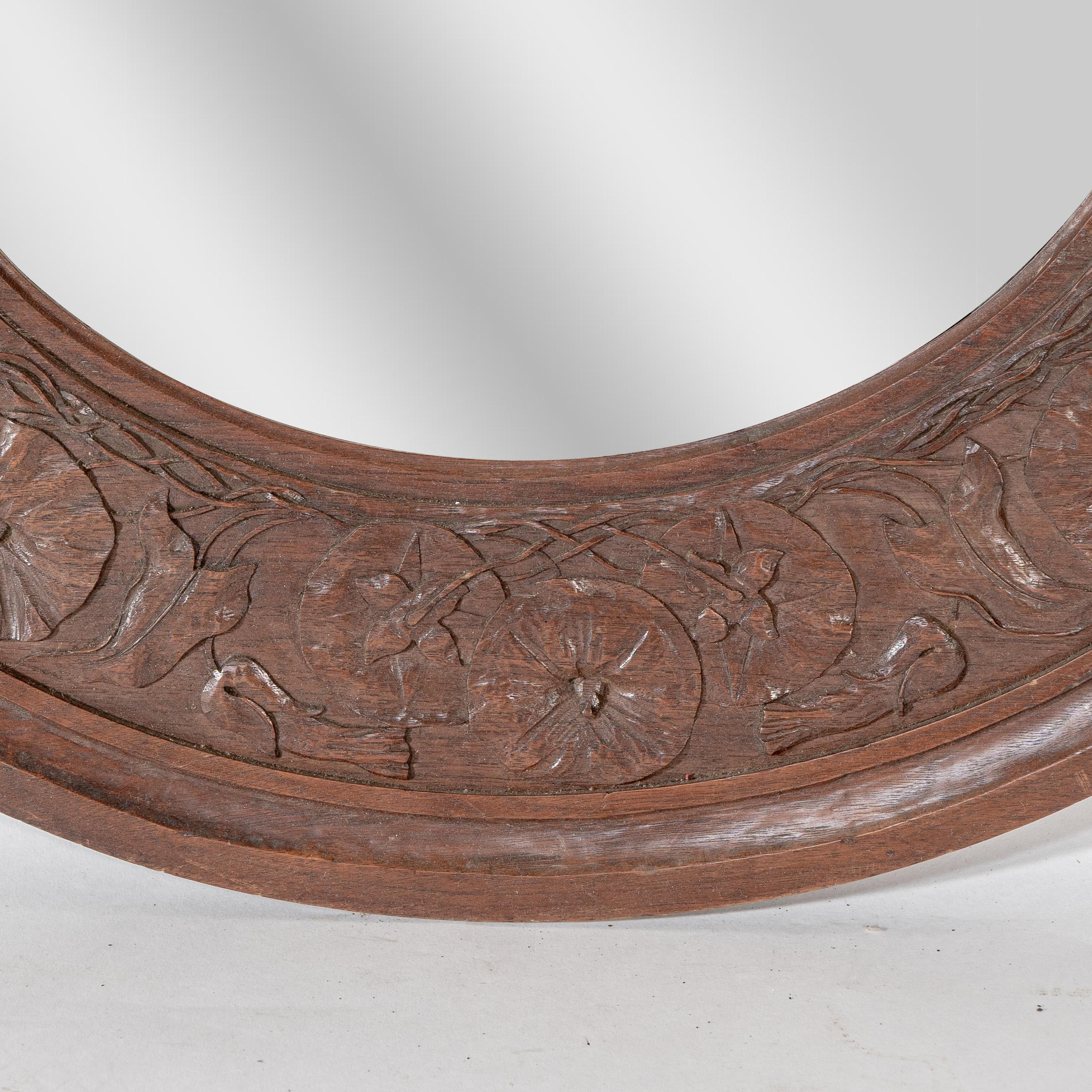 Walnut An Arts & Crafts walnut circular mirror with stylized floral carved decoration For Sale