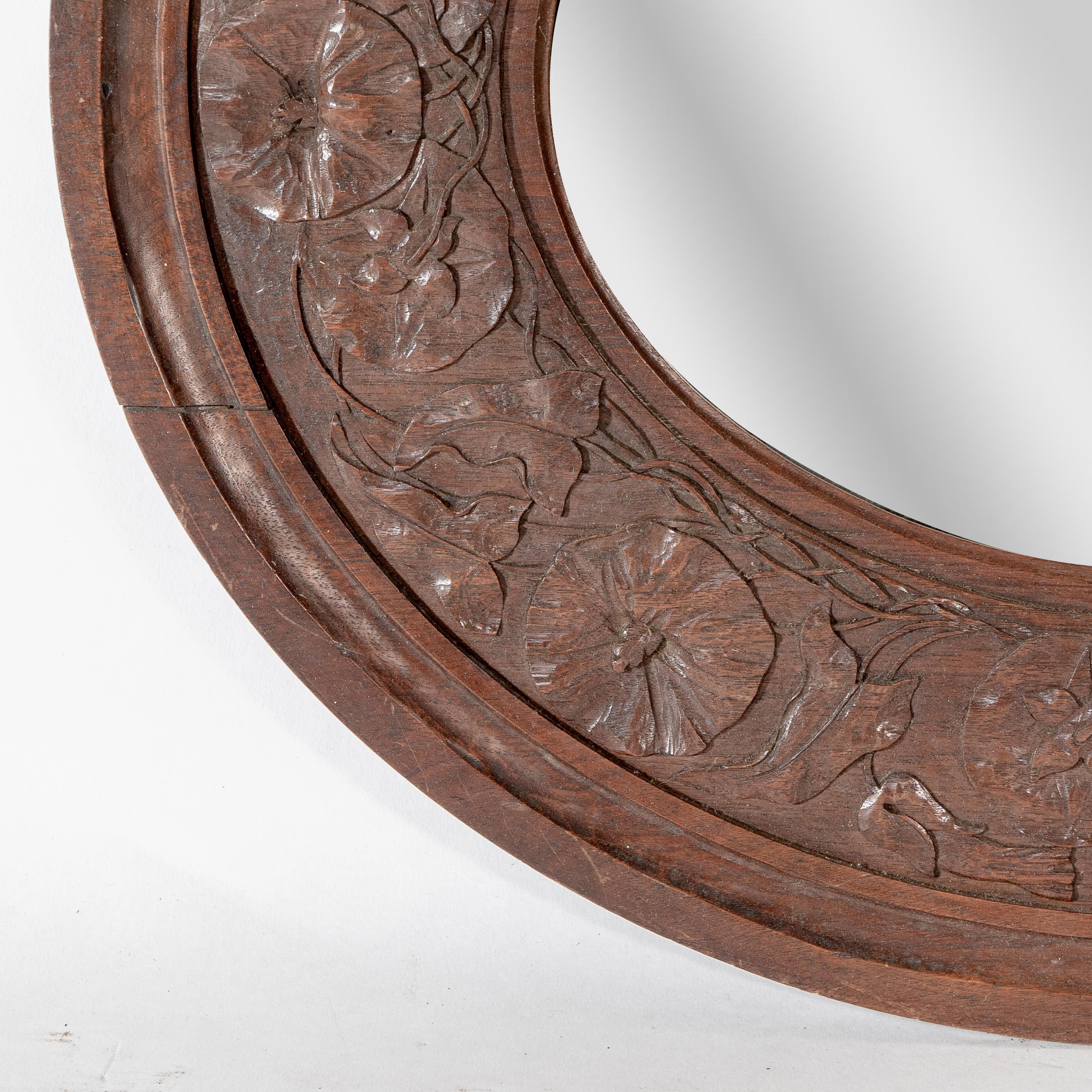 An Arts & Crafts walnut circular mirror with stylized floral carved decoration For Sale 1