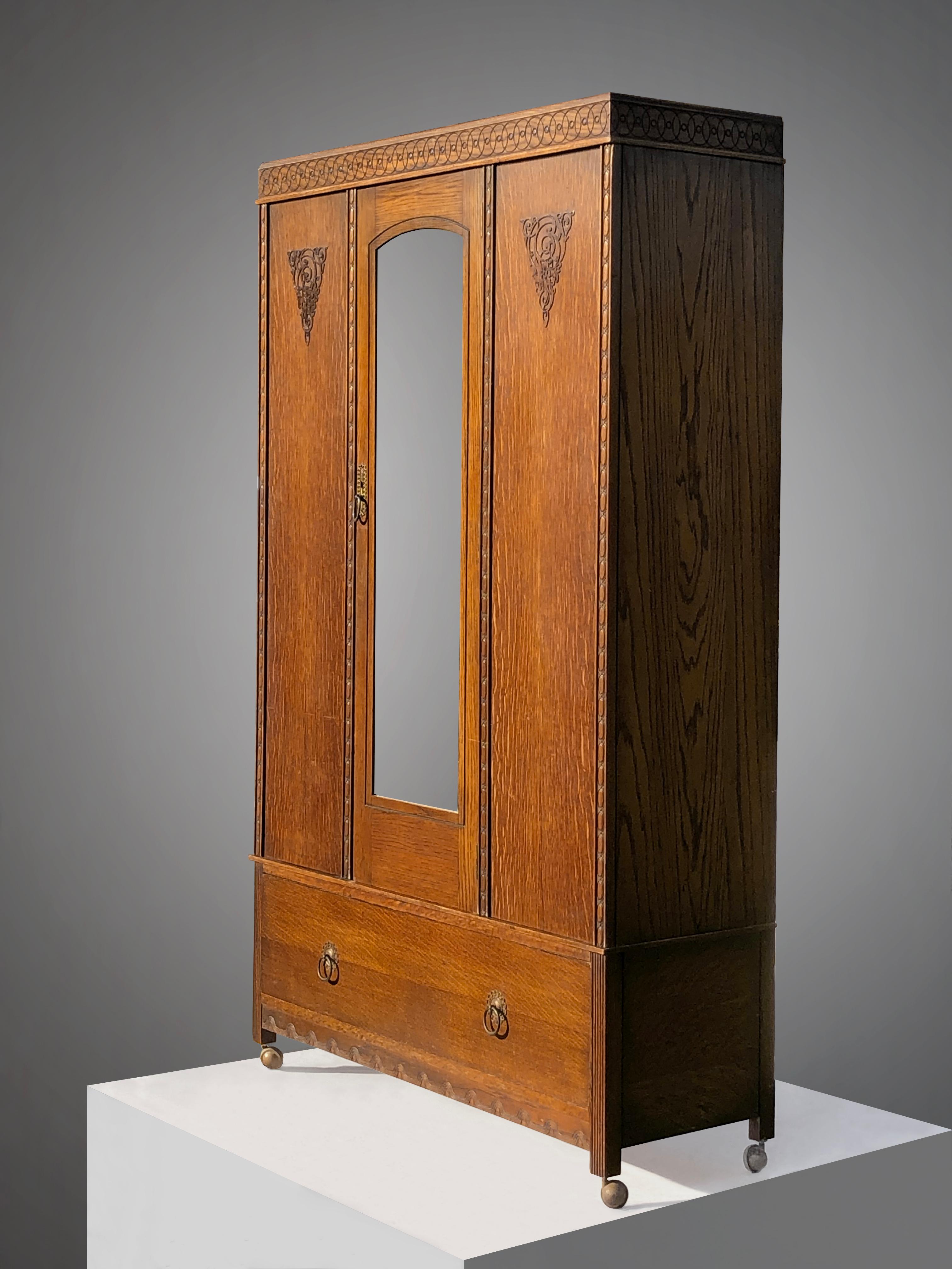 A large wardrobe cabinet, superb wood vertical structure enhanced by beautiful geometric ornaments, with 1 central mirrored door opening on 3 hanging systems and one major drawer at the bottom, by Harris Lebus, UK 1900-1910. 

This beautiful cabinet