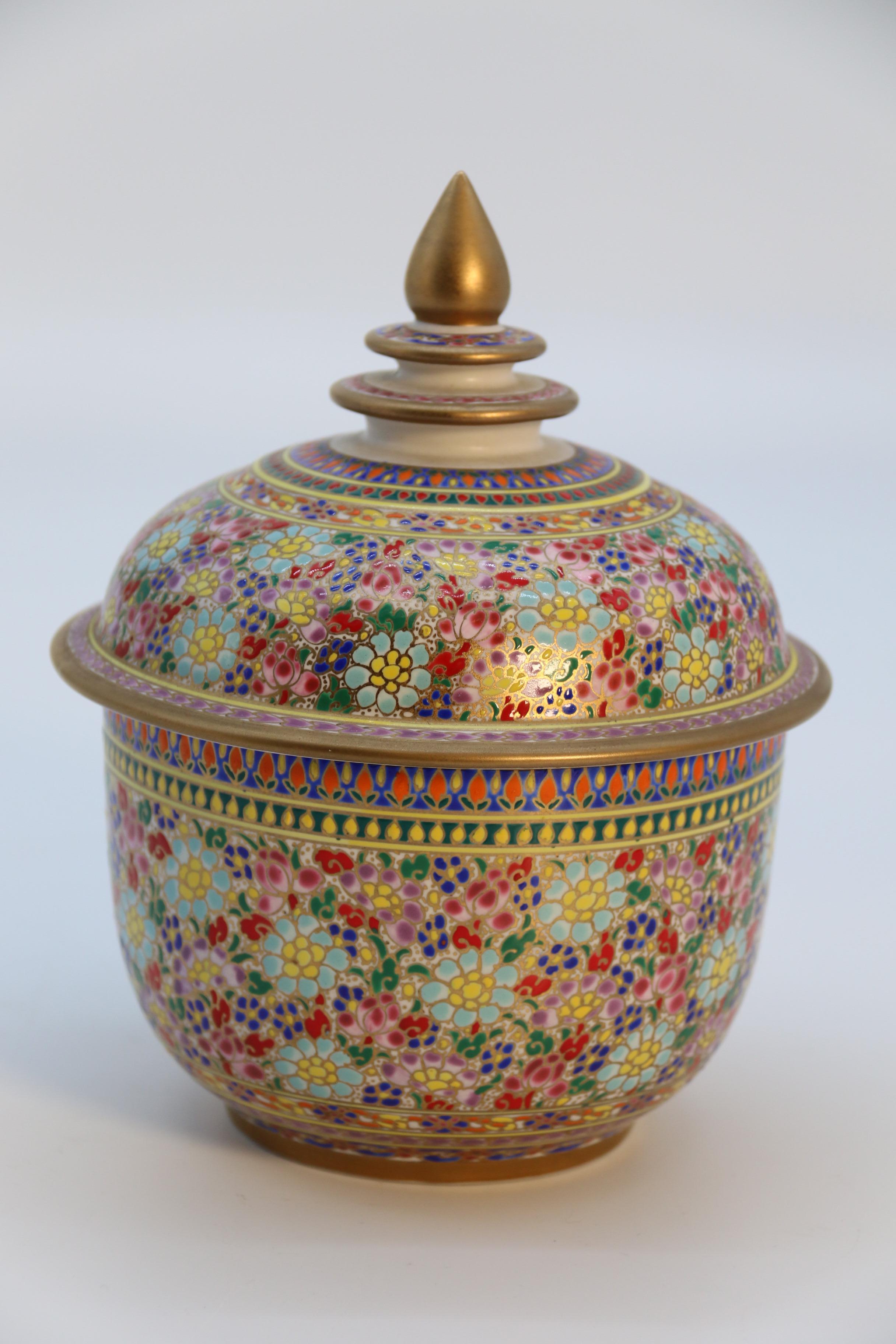 This beautiful and most eye catching early 20th century Siam pottery lidded jar has a jewel like quality. It has been richly decorated with a very fine hand painted radiating diamond design which is separated throughout the body and lid with