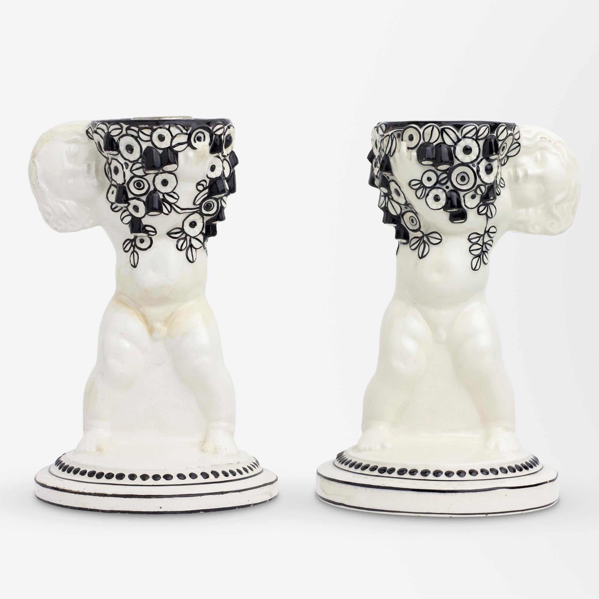 Paire de bougeoirs en céramique de la Sécession viennoise en forme de putti tenant des fleurs, réalisés par Michael Powolny pour Weiner Keramik dans son style noir et blanc, vers 1907. Ces chandeliers sont devenus une paire à un moment donné de leur