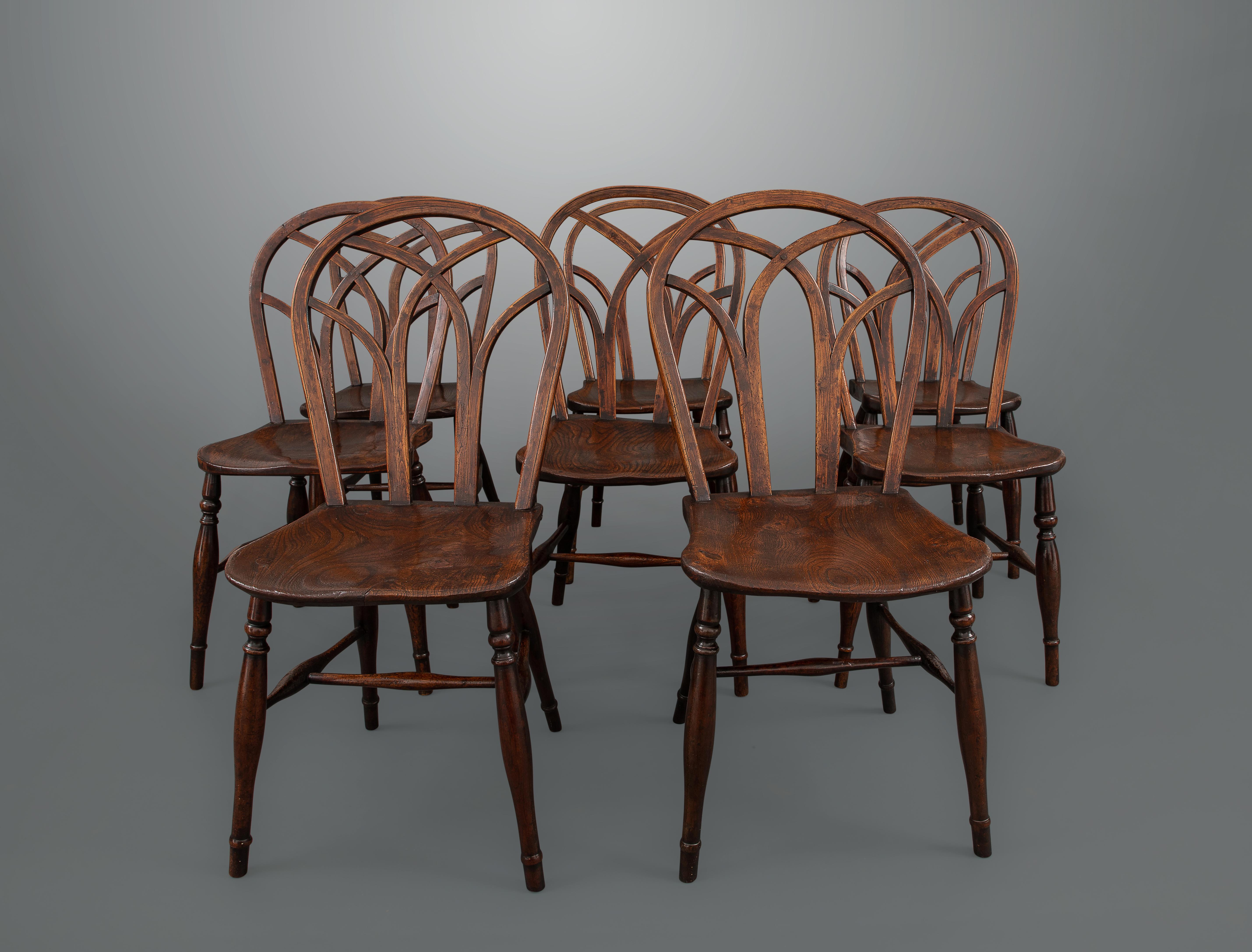All in beech with ash backs and elm seats, five of the chairs are stamped with the makers initials T. B. Each chair has single ring and concave turned legs with lower ring and straight turned feet with the legs connected by H-form elliptical turned