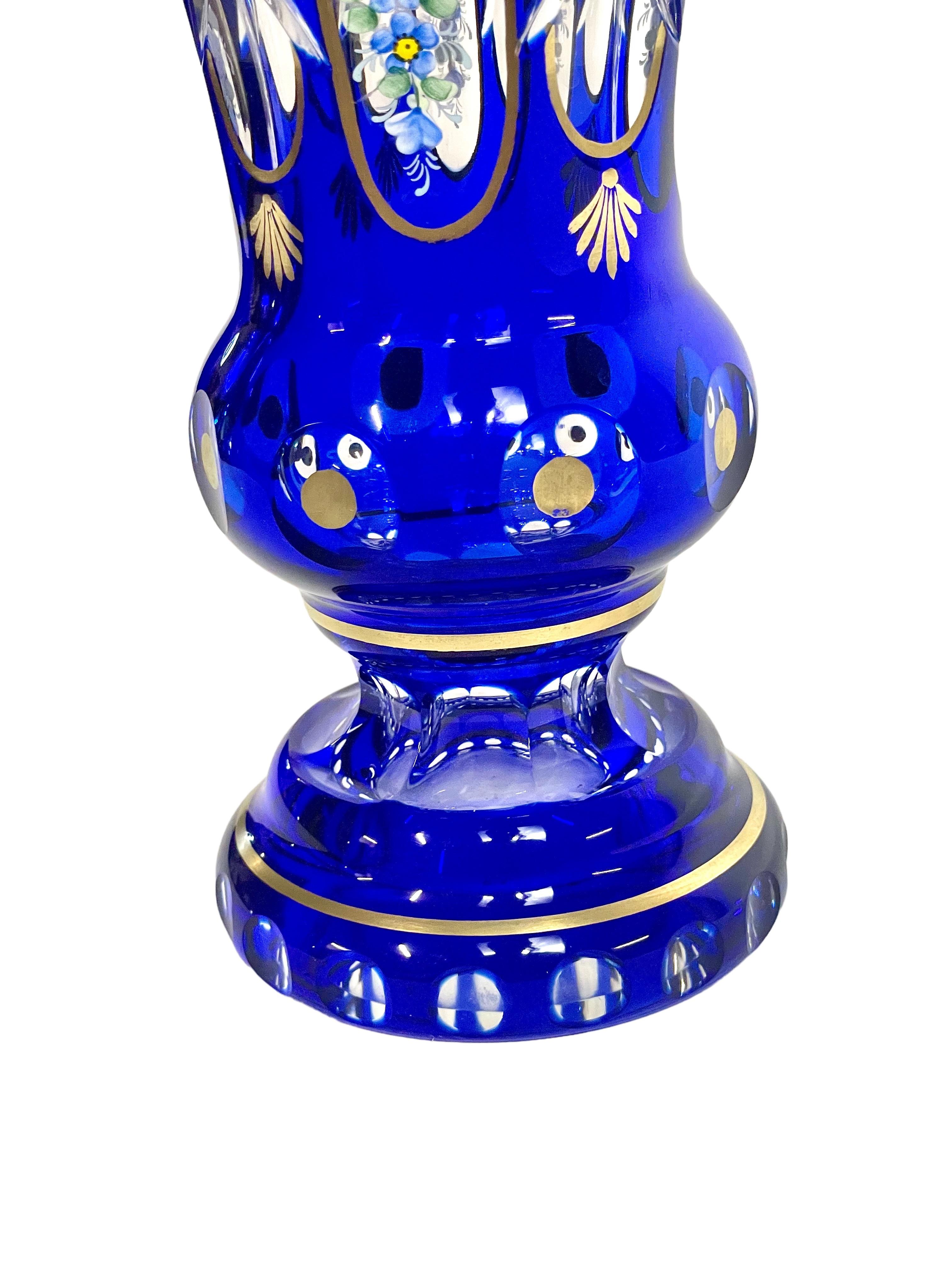 An attractive cobalt-blue crystal overlay footed urn vase, hand-blown and cut, and painted with enamel flower motifs and intricate gold trimming. This Bohemian-style vase would be a marvellous addition to a vintage bedroom décor, or on an ornate