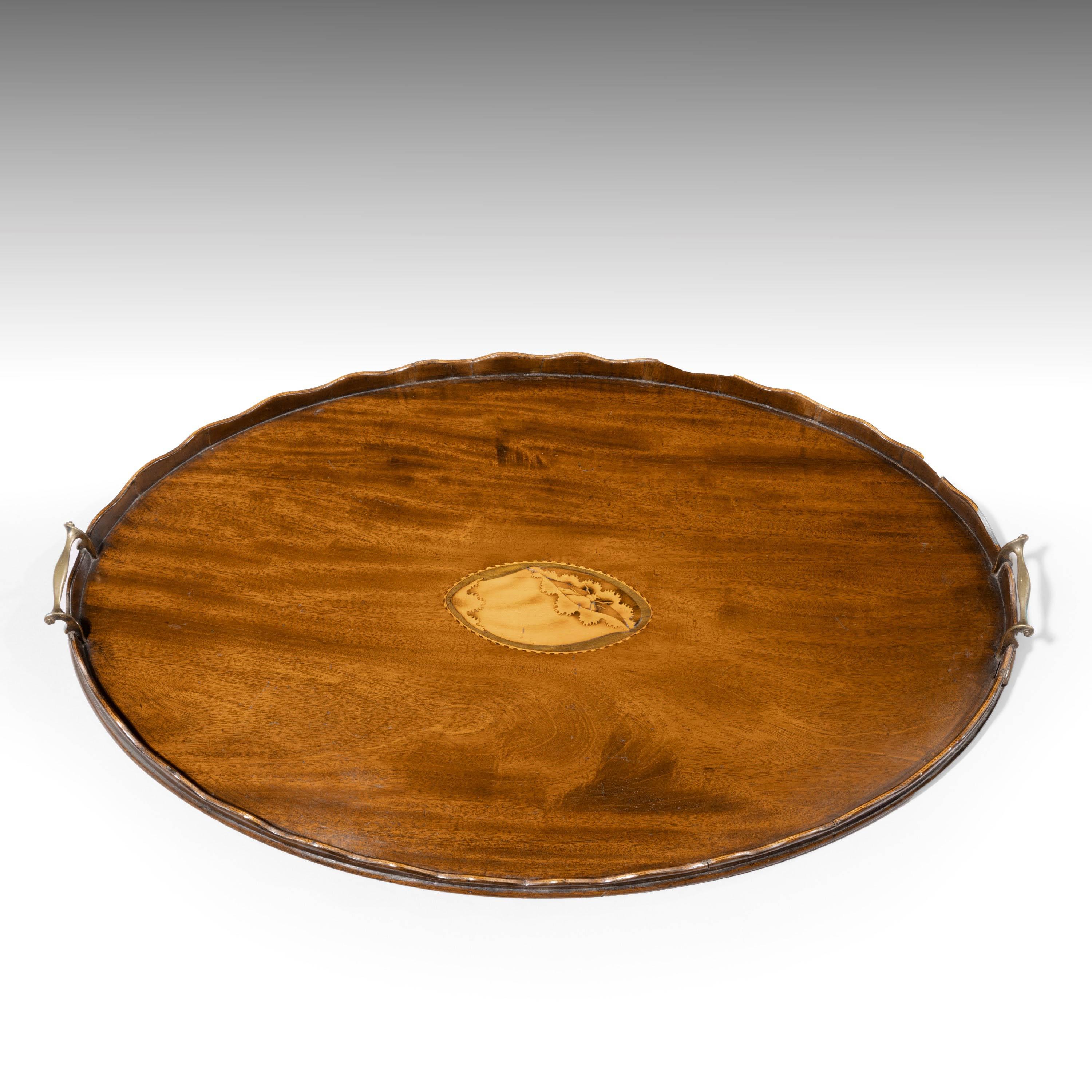 An attractive Edwardian mahogany oval tray. With the original gilt bronze handles and a wavy border. The centre with a fine inlaid marquetry shell.
  