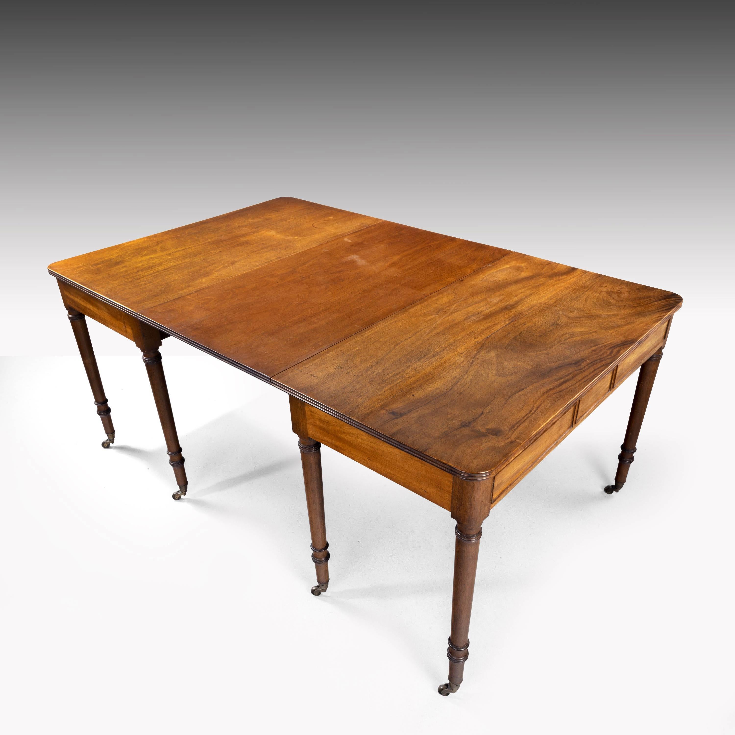 An attractive George III mahogany dining table. Can also be used as a pair of pier tables. A particularly good rich honey color. The top with a reeded edge over well-turned tapering supports. Retaining the original shoes and castors.
    