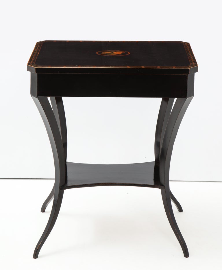 An elegant Austrian Empire ebonized fruitwood side table with fruitwood and stencil work, circa 1820s, the rectangular top with canted corners above a single frieze drawer raised on generous incurved legs joined by a low stretcher.