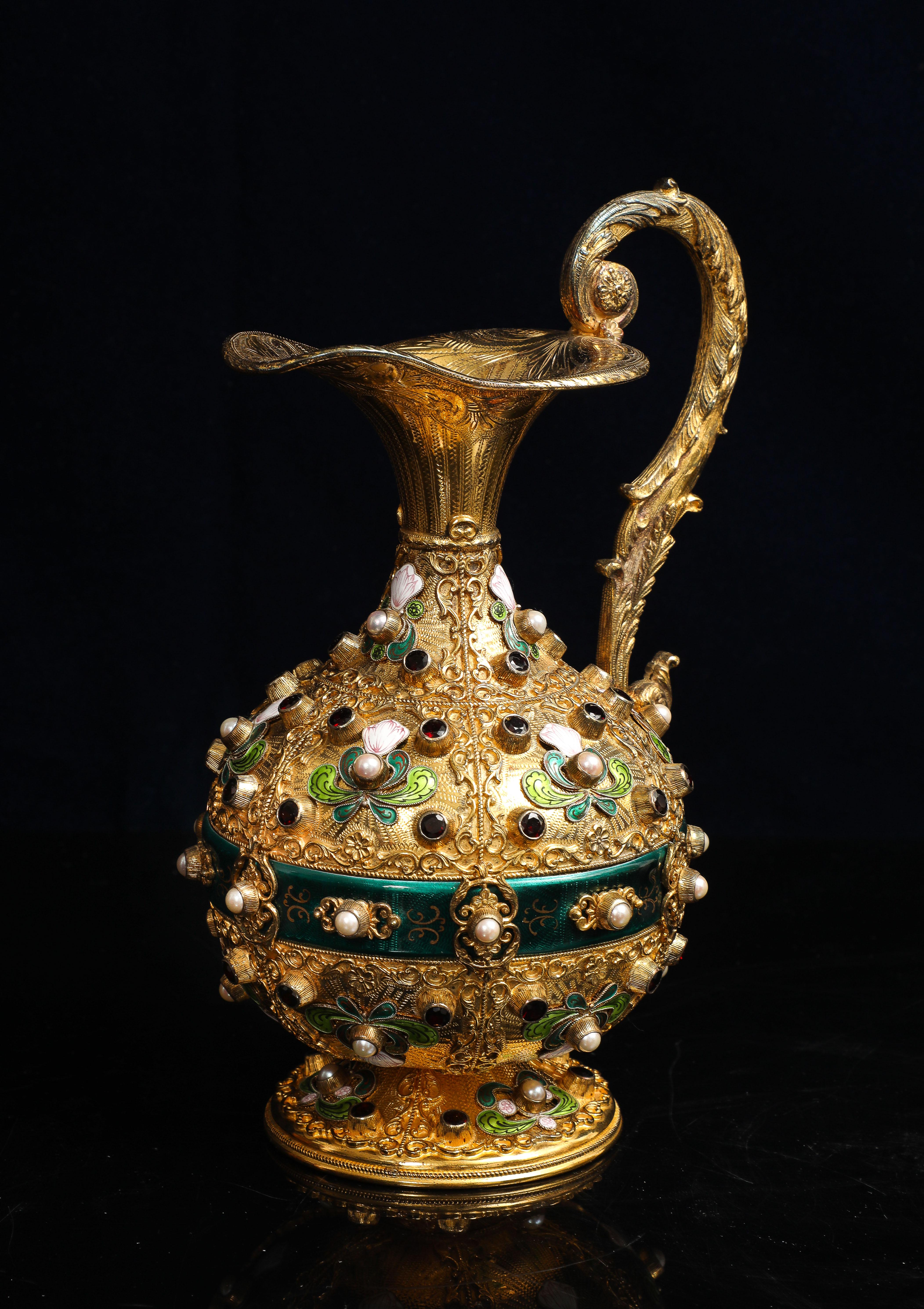 Eine österreichisch-ungarische, mit Halbedelsteinen besetzte, emaillierte und vergoldete Silberkanne.  Eine österreichisch-ungarische, vergoldete Silberkanne in bauchiger Form, mit Halbedelsteinen besetzt und mit polychromer Emaille verziert. Der