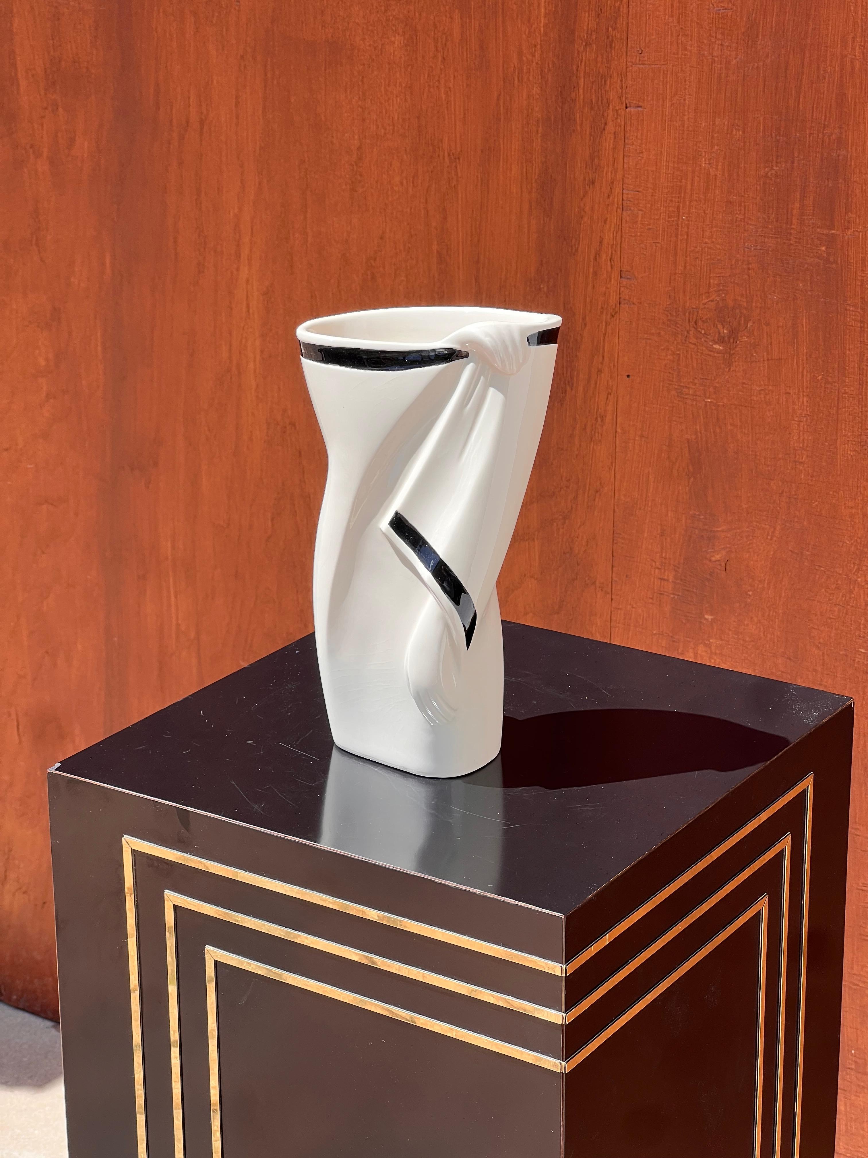 An elegant postmodern vase featuring a cloaked figure by Lindsey B., signed, 1983. Tones of snow and licorice. 
5” W x 3.25” D x 8.75” H 