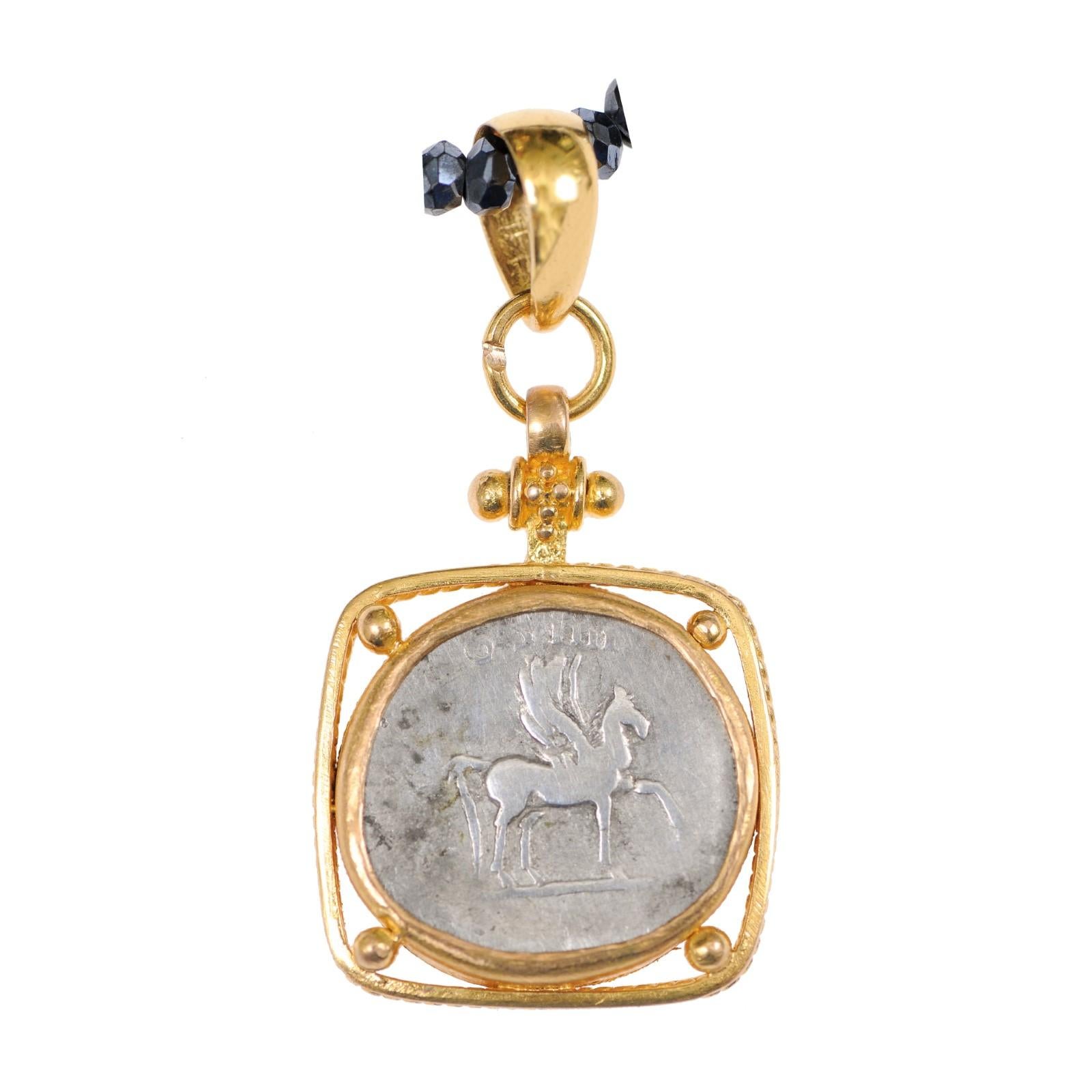An authentic Roman Empire, Domitian (circa 81-96 AD), silver coin, set in a custom 22-karat gold bezel, suspended design with gold ball accents, and a 22-karat gold bail. The obverse, or front, side of this coin features Domitian, with Pegasus,