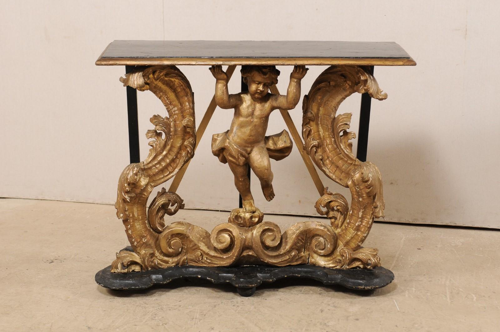 An exquisite Italian Rococo carved wood and gilt console table with putto from the early 18th century, possibly 17th century. This period Rococo wall console from Italy features a three-dimensionally hand carved wood putto, with loincloth loosely